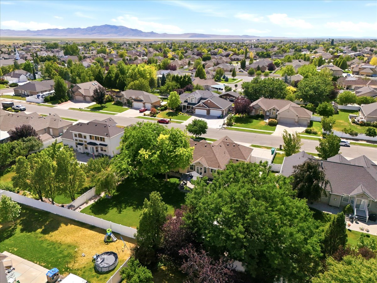 Expansive neighborhood featuring mature trees, paved streets, and a mountainous backdrop.Aerial view from the back of the home.