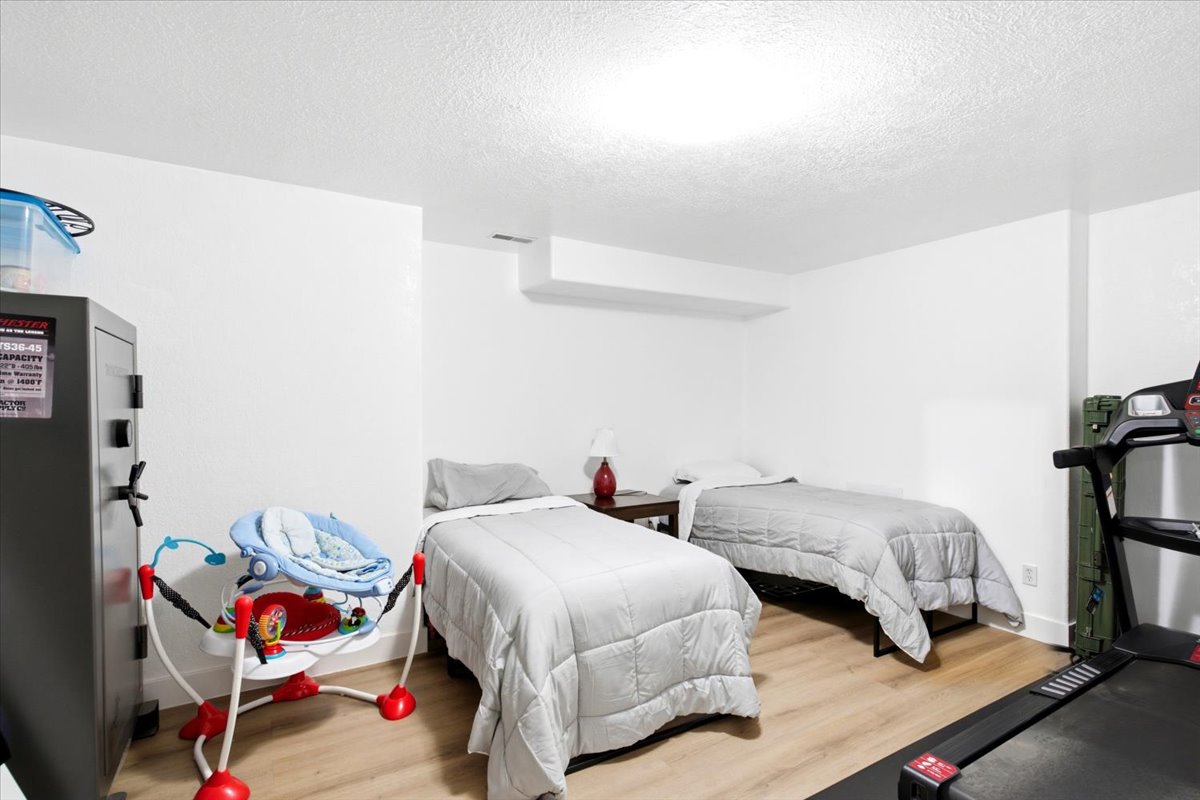 Spacious room featuring light wood-finish flooring, white painted walls, and a white ceiling with recessed lighting