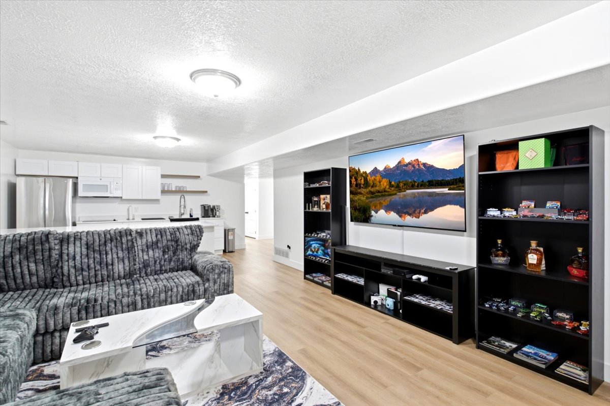 Spacious living area featuring light wood-finish flooring and recessed lighting