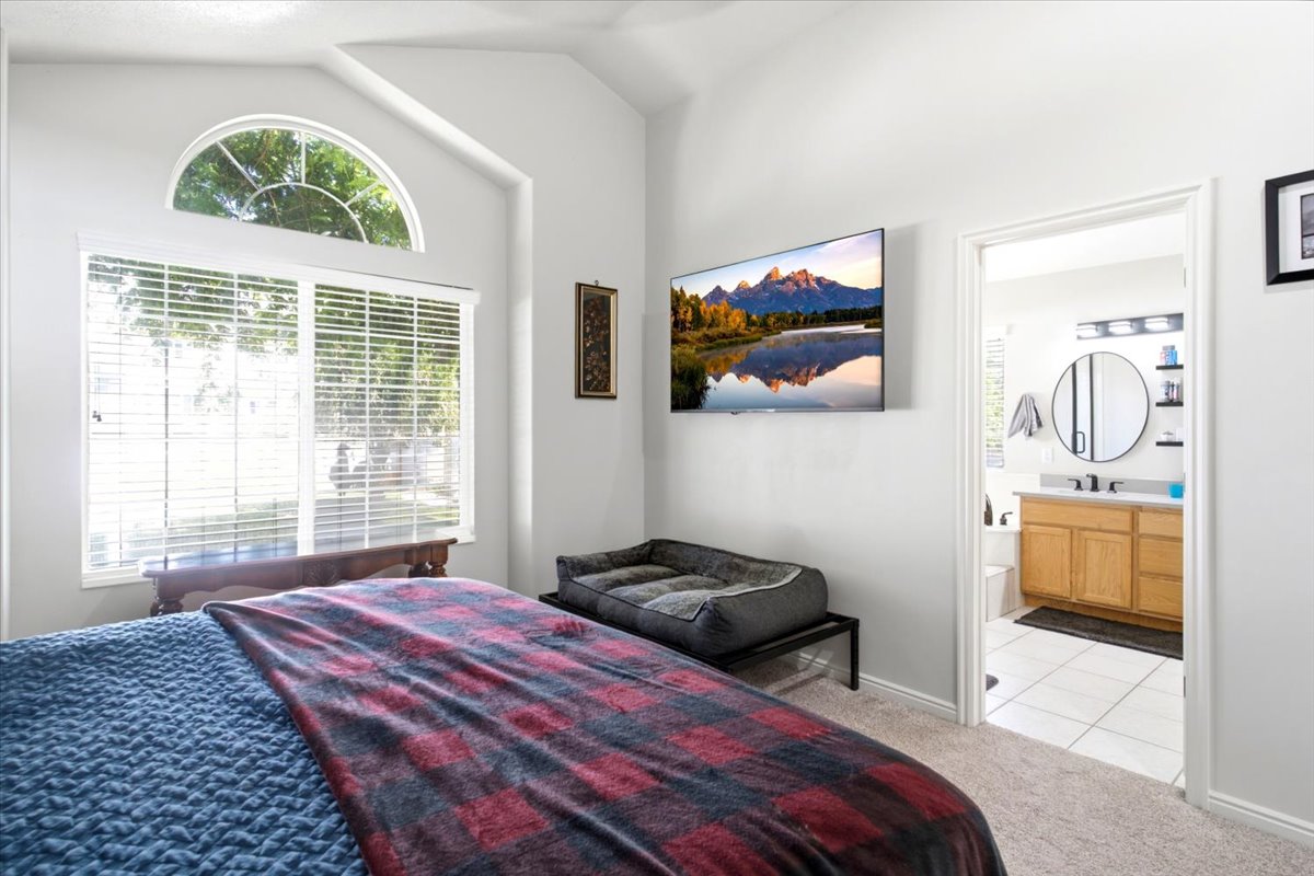 Primary bedroom with vaulted ceiling, a large window, and an arched transom, providing ample natural light