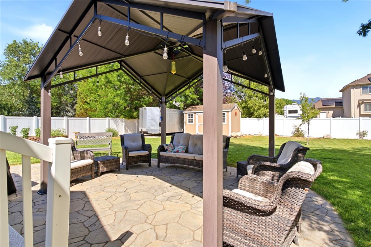 Expansive backyard featuring a stone patio and a large, covered gazebo with string lighting