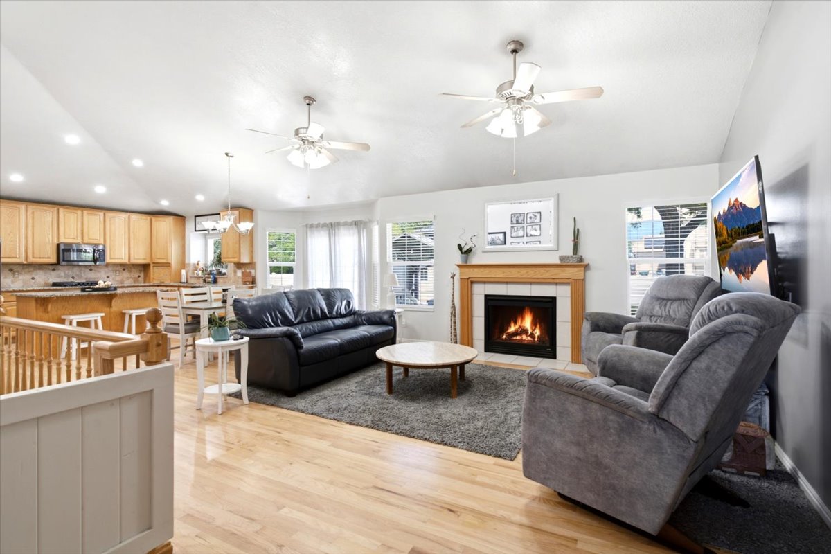 Open-concept living area featuring a gas fireplace with a wood mantle, light wood-finish flooring, and white walls