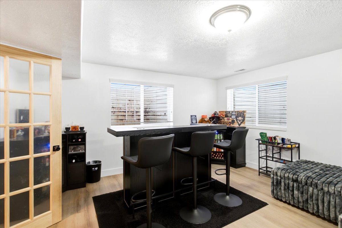 Downstairs living area space featuring wood-finish flooring, recessed lighting, and windows with horizontal blinds