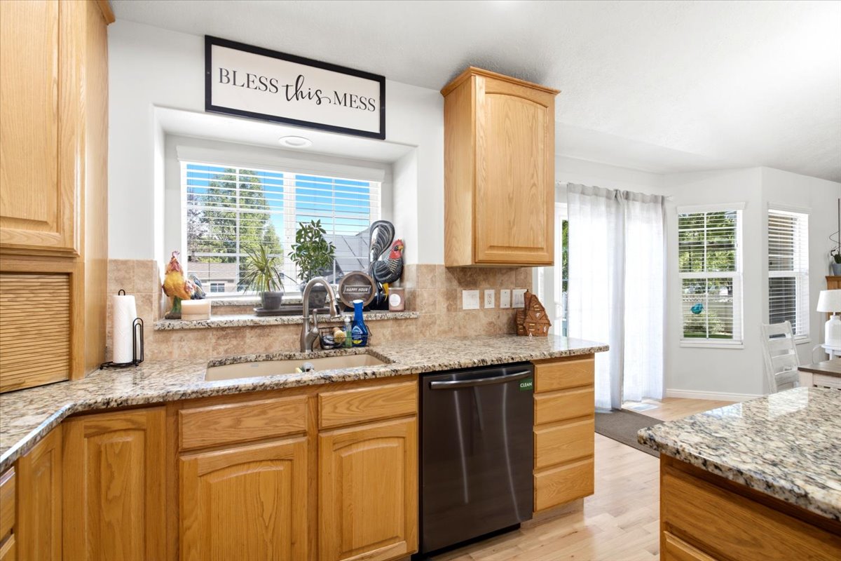 Kitchen featuring light wood cabinetry, granite-style countertops, a stainless steel sink, and a tiled backsplash