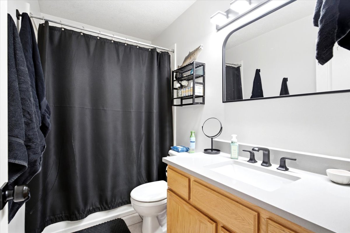 Bathroom featuring a shower/tub combination, single vanity, and wood-finish cabinetry