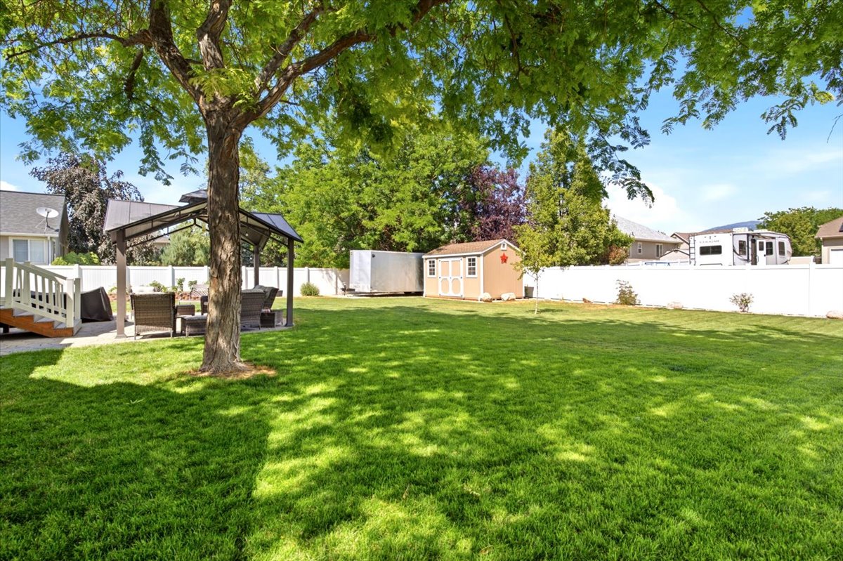 Expansive green lawn with mature trees and a dedicated patio area