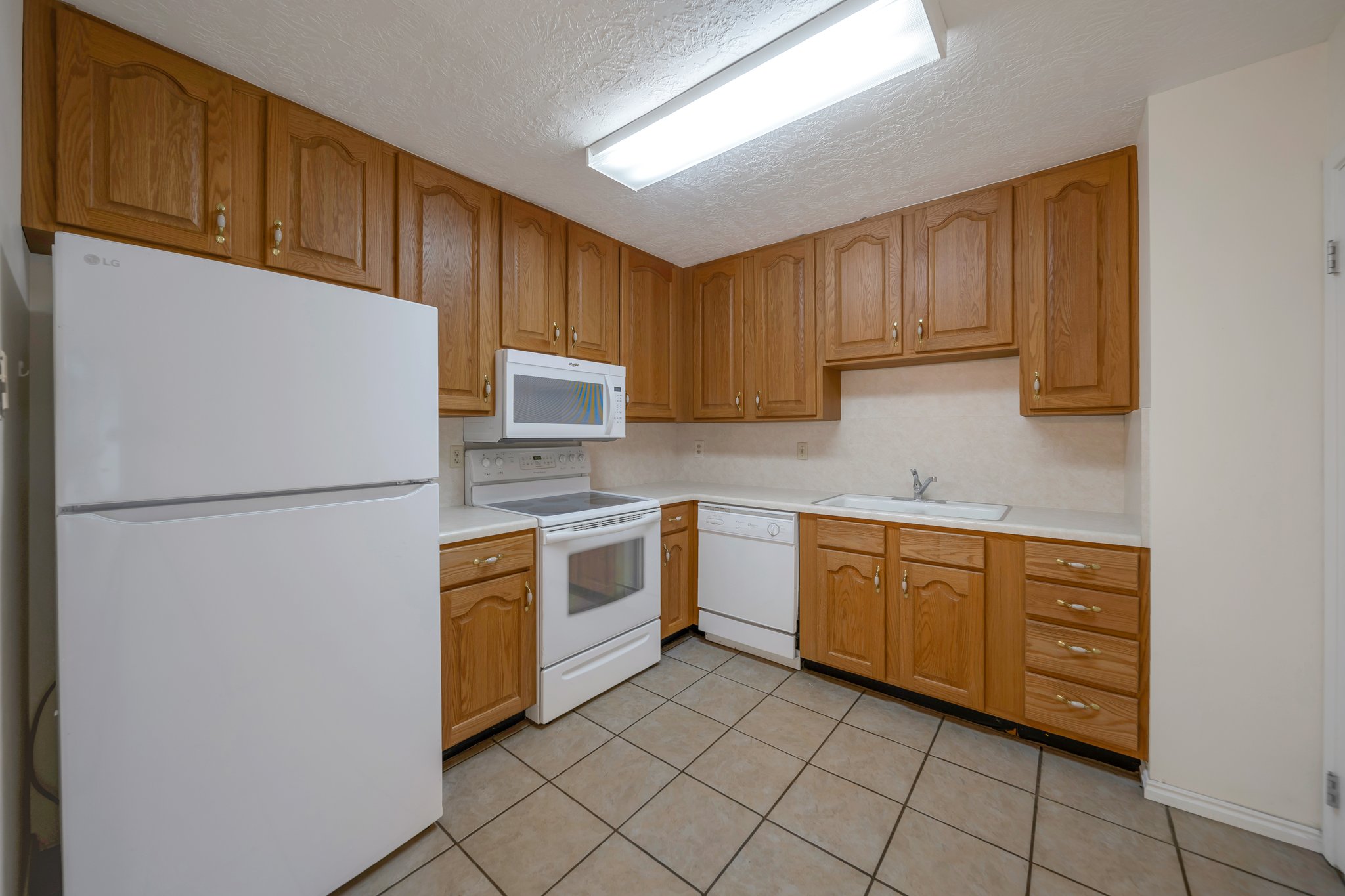 Kitchen featuring wood cabinetry, light countertops, and tile flooring