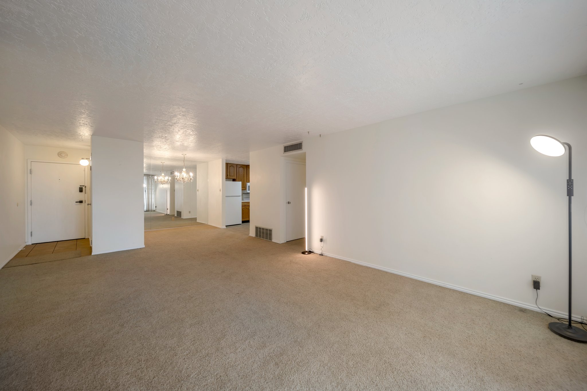 Spacious carpeted living area with white walls and textured ceilings