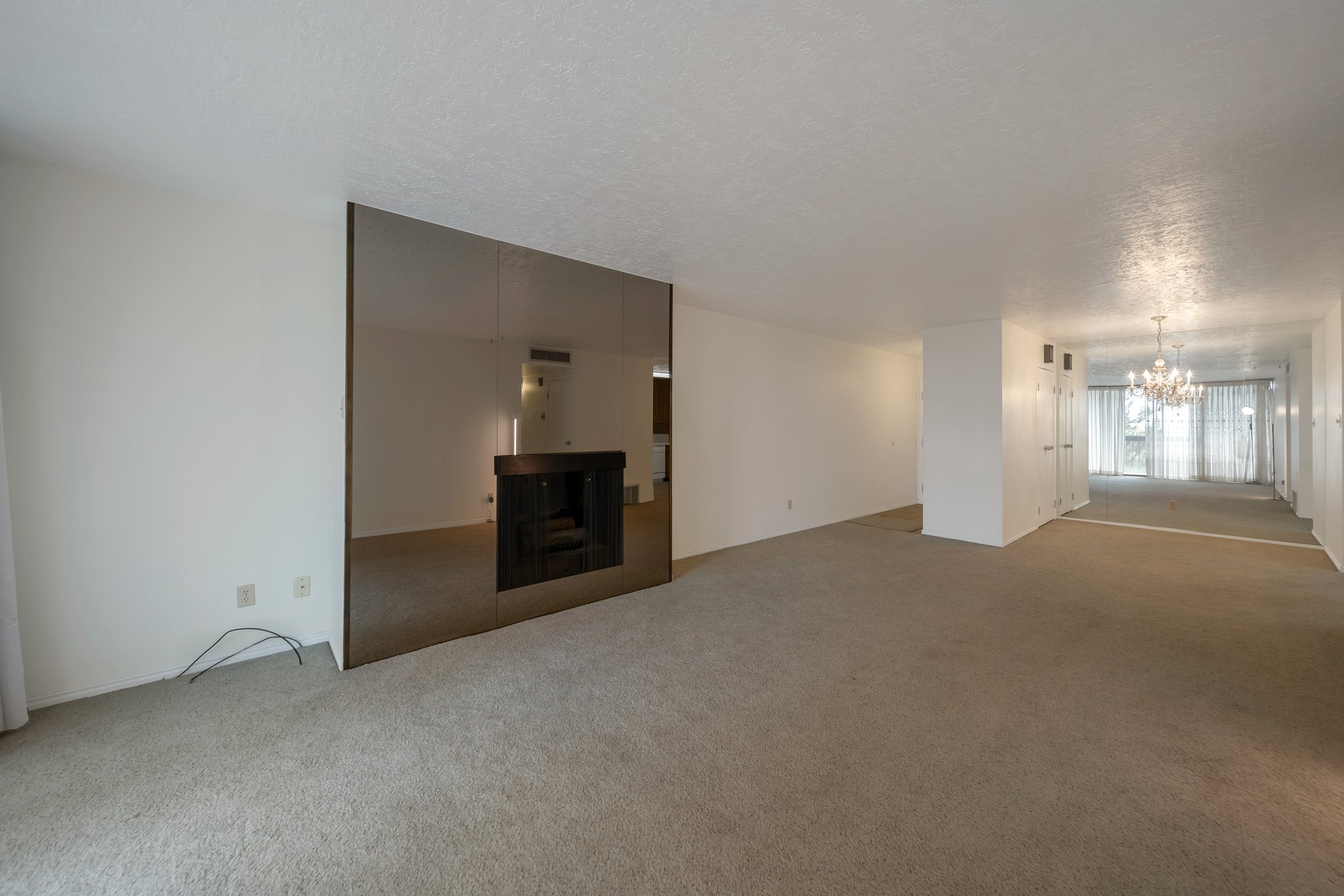 Living area featuring a mirrored fireplace surround and light tan carpeting