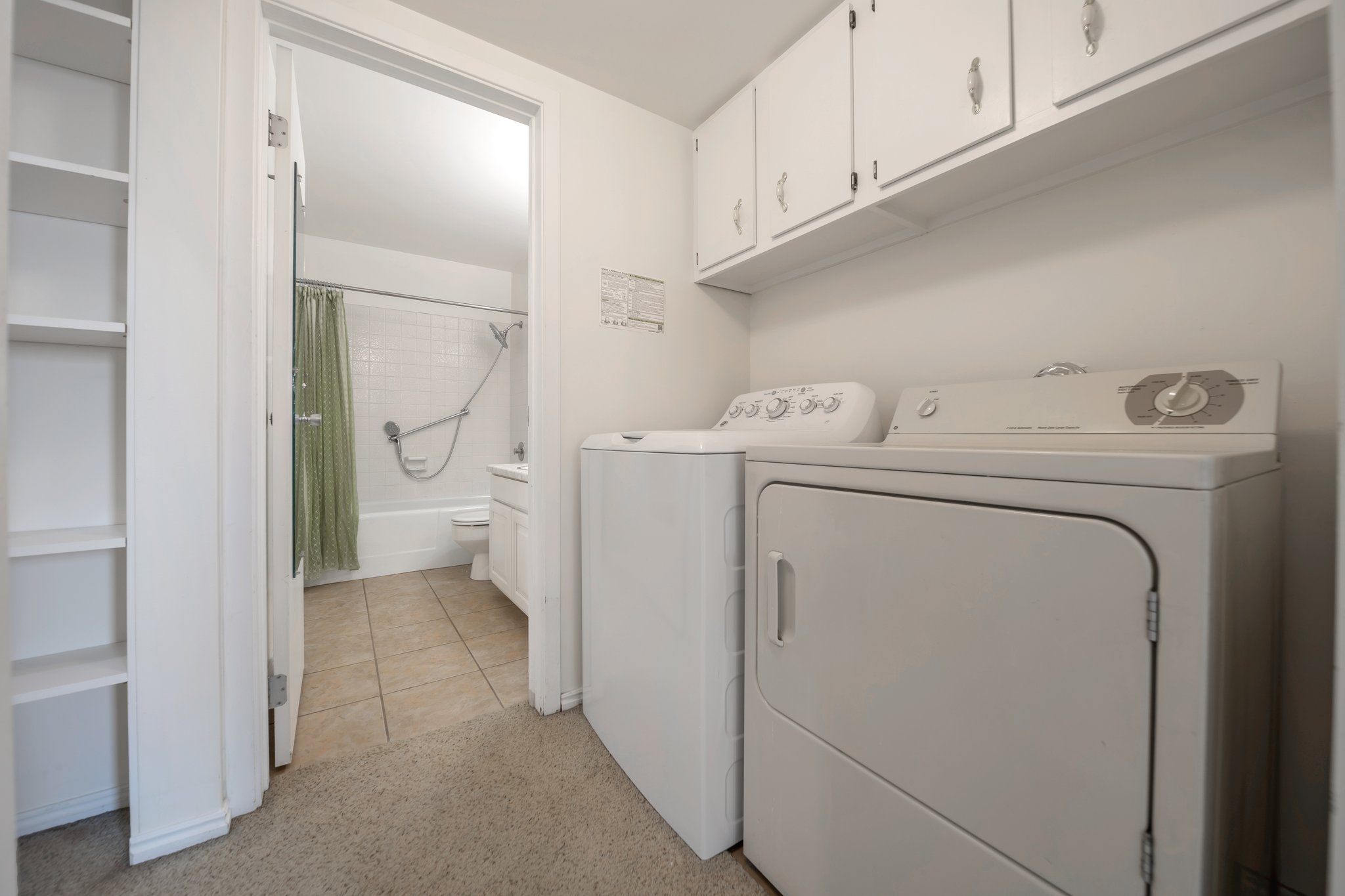 Dedicated laundry area featuring upper cabinetry and built-in shelving