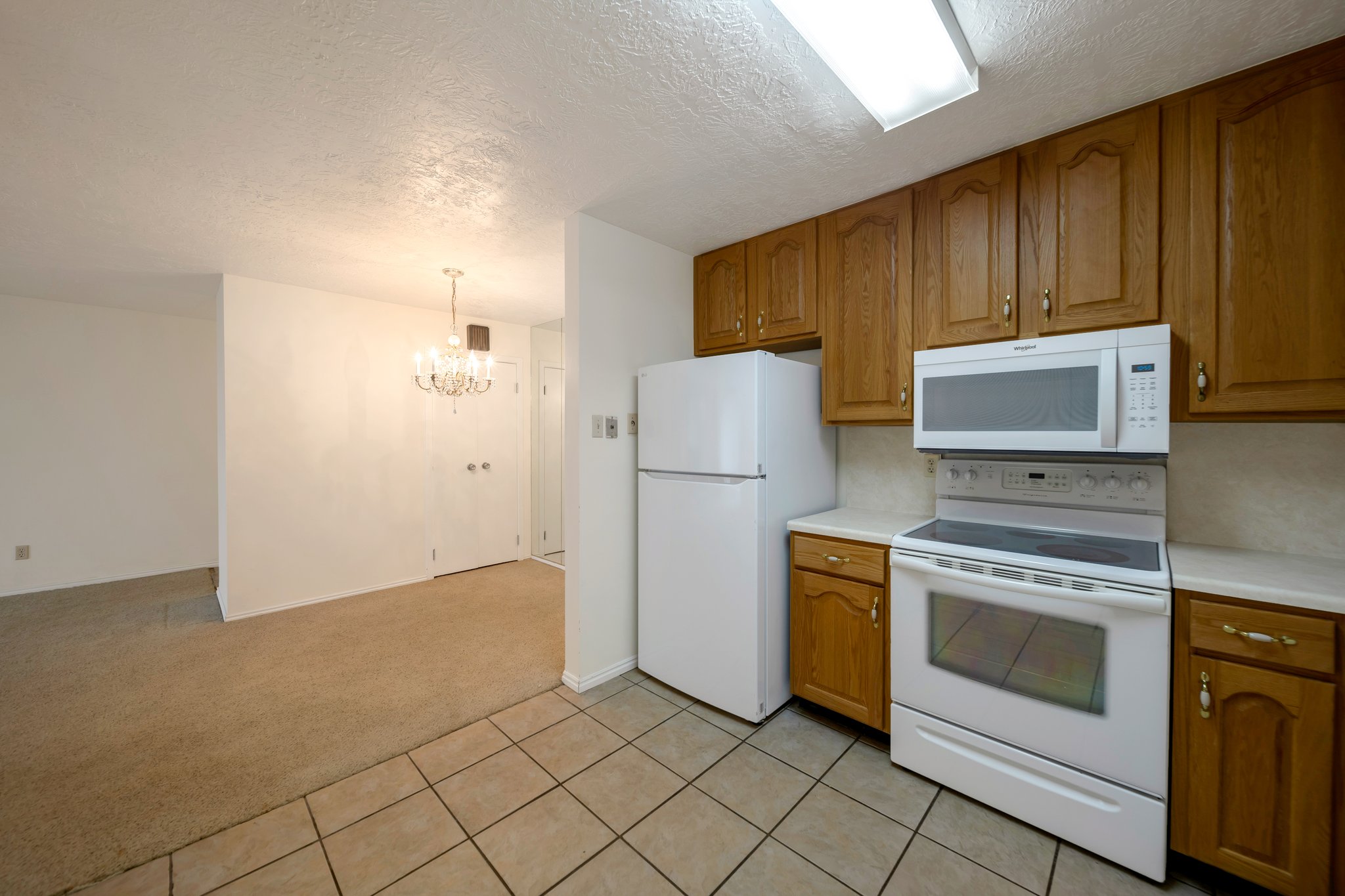Kitchen space featuring a white electric range, white over-the-range microwave, and a white refrigerator