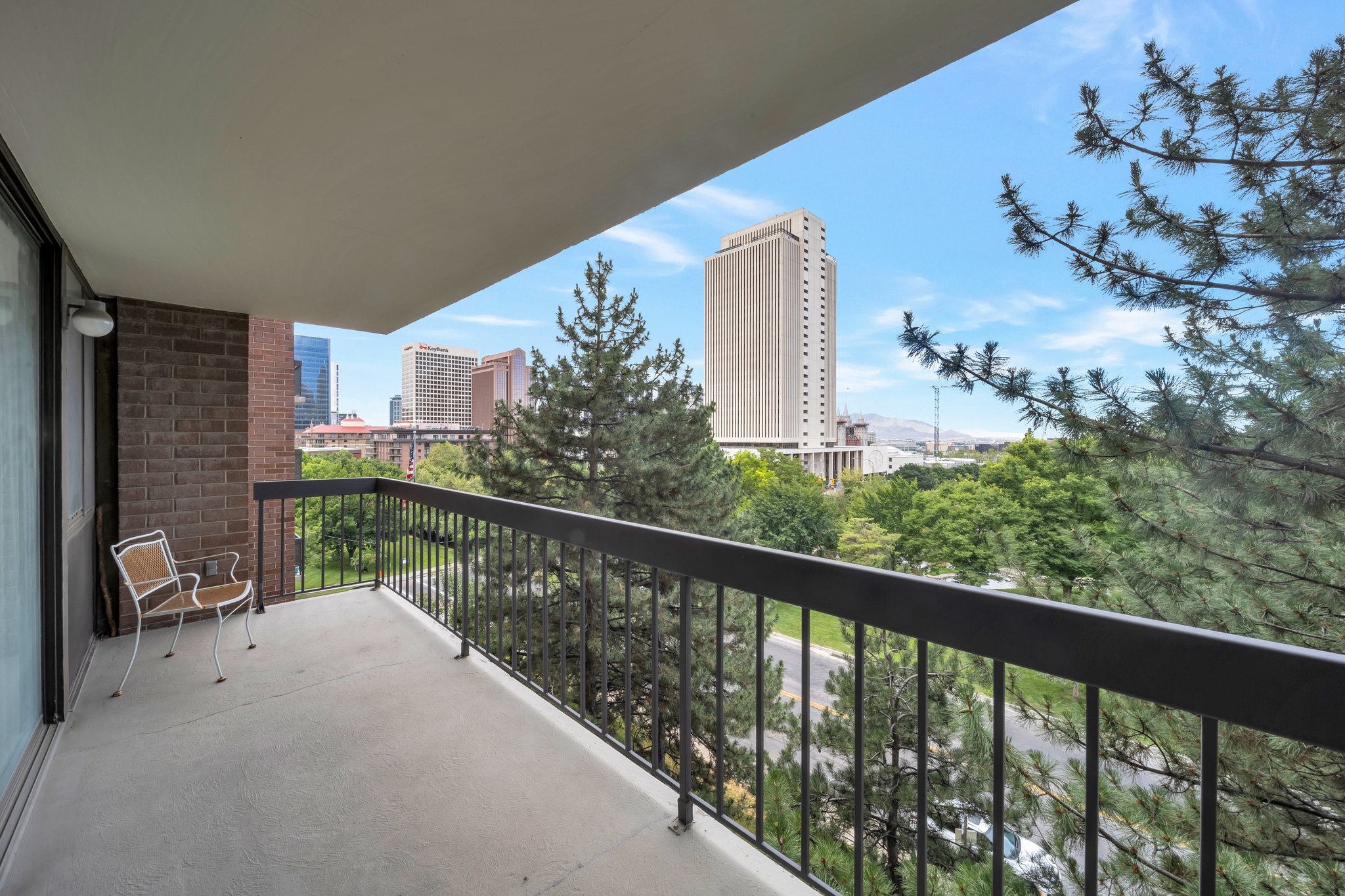 Private balcony featuring concrete flooring, a black metal railing, and a brick exterior wall