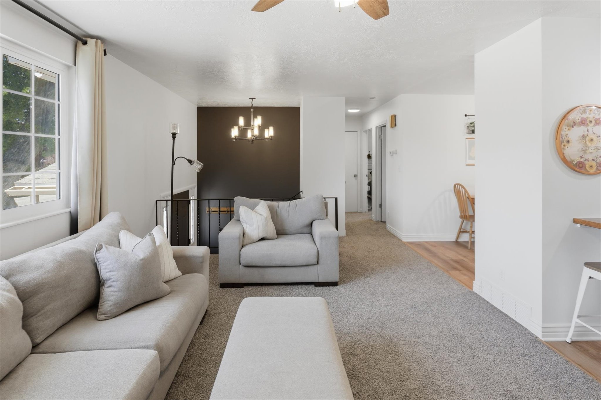 Spacious living area featuring light gray carpeting, white walls, and a prominent window with grid detailing