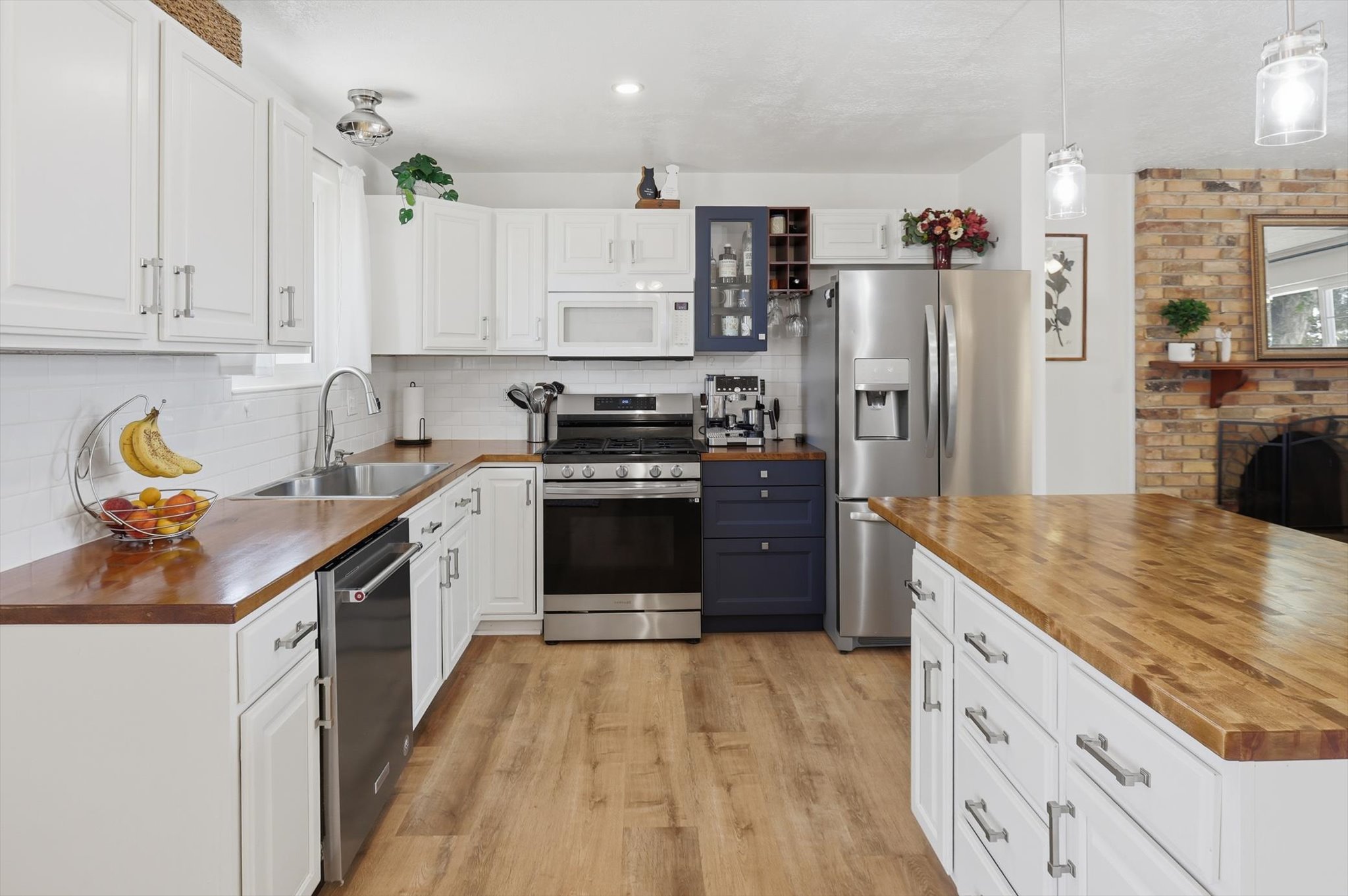 Kitchen featuring wood-finish countertops, white cabinetry, a large center island, and stainless steel appliances