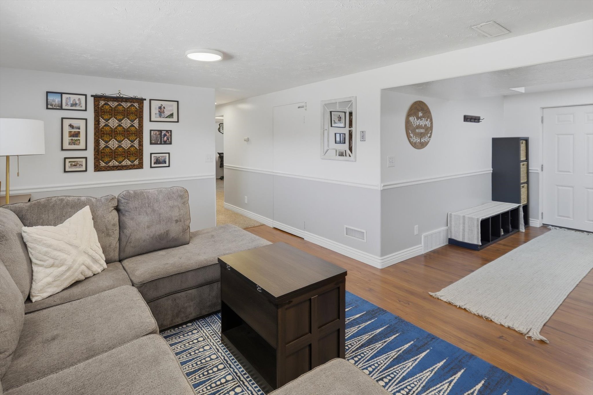 Spacious living area featuring wood-finish flooring, white baseboards, and two-tone wall paneling