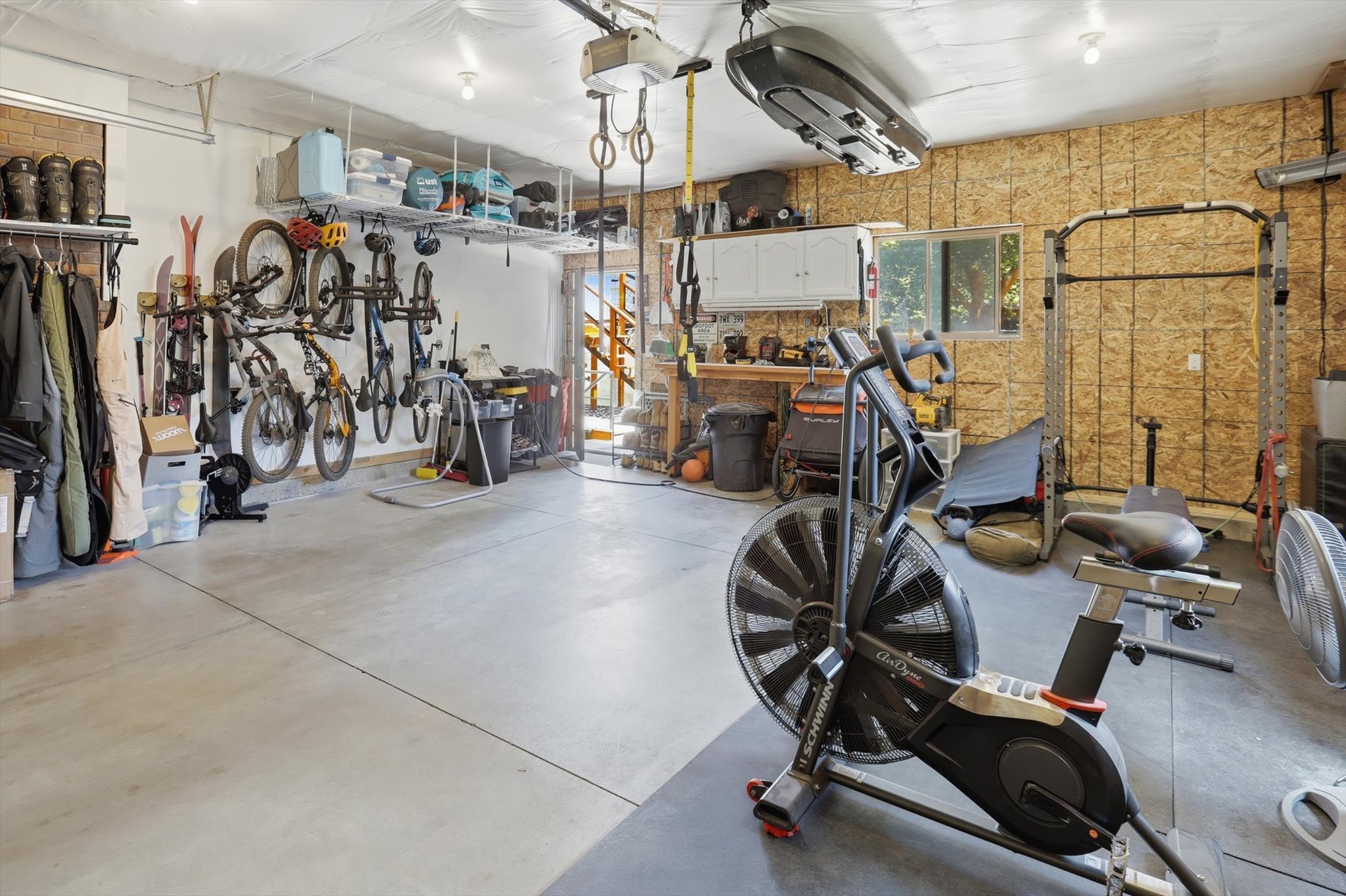 Spacious garage featuring a concrete floor, exposed wood paneling, and an overhead storage rack