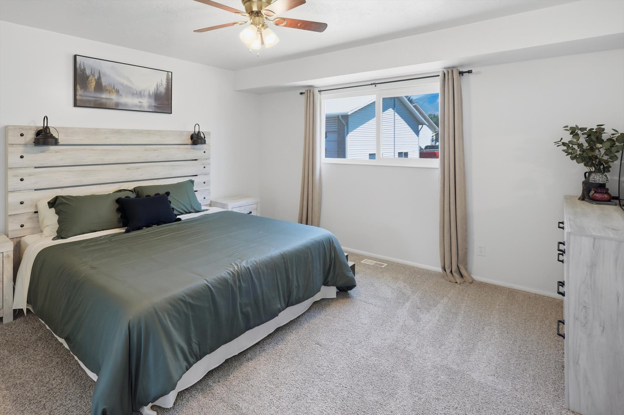Carpeted bedroom with a built-in wood-finish headboard featuring wall-mounted sconces
