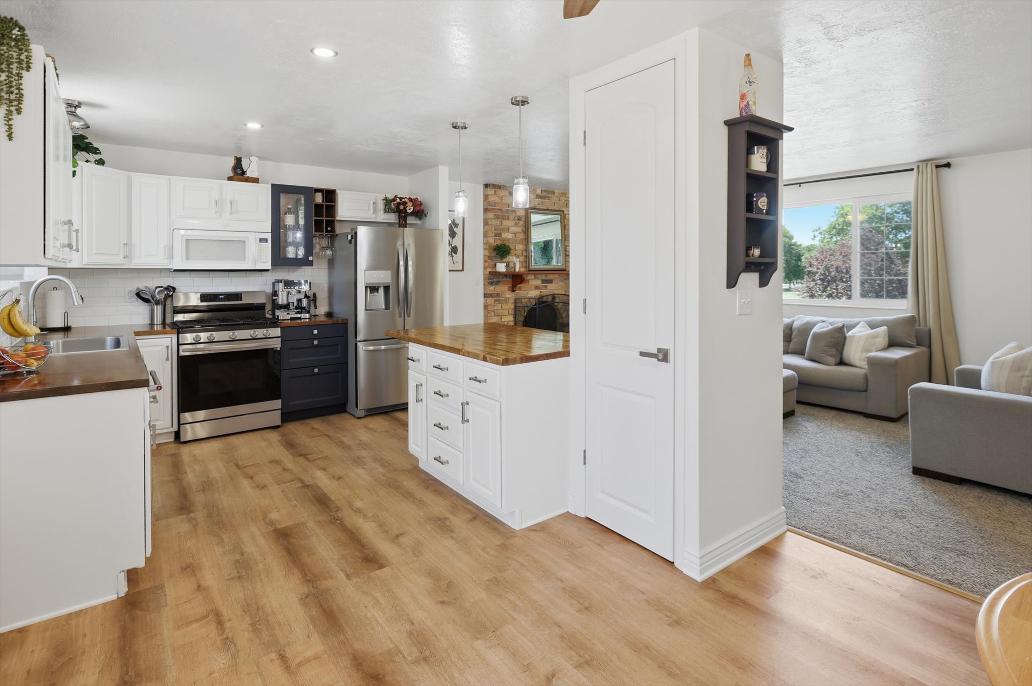 Contemporary kitchen with wood-finish flooring, white cabinetry, stainless steel appliances, and butcher block countertops