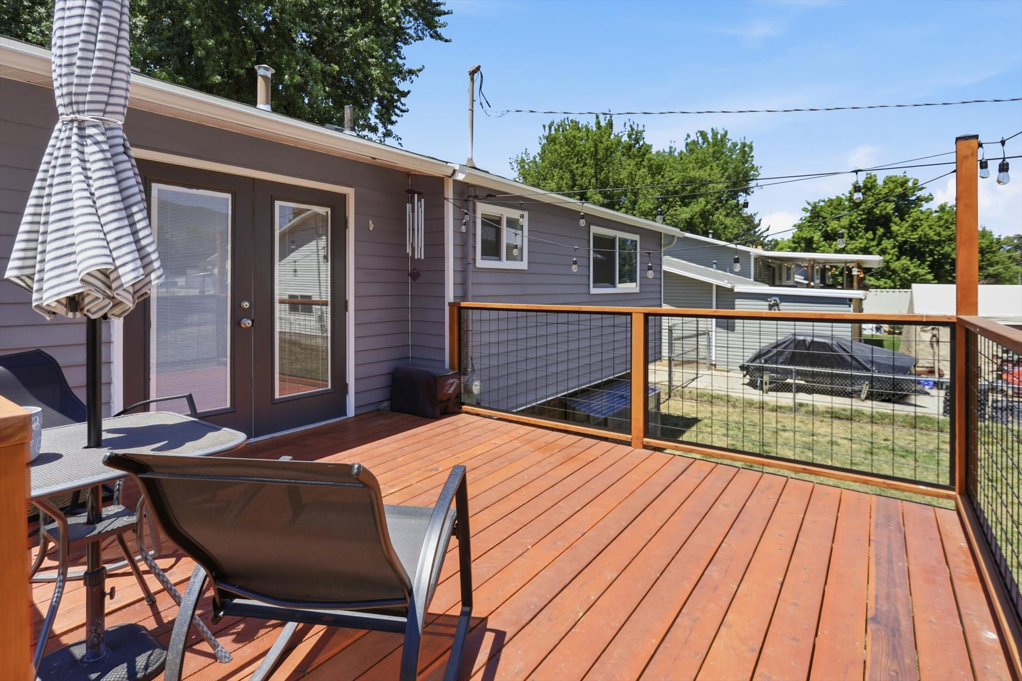 Expansive wood deck featuring a wire mesh railing system and a gray siding exterior