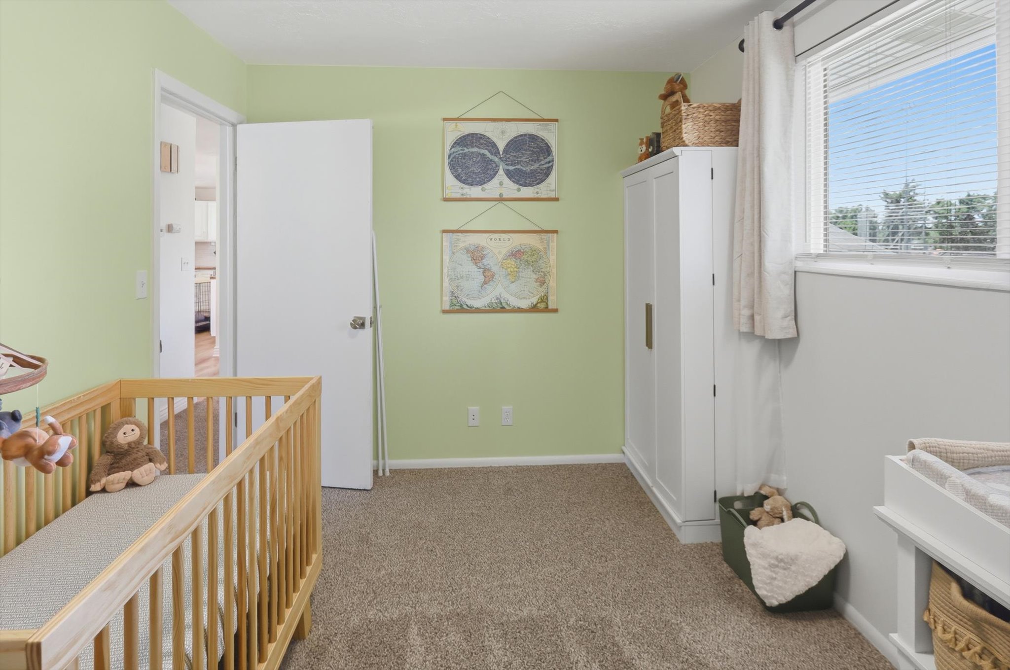 Carpeted room featuring light green walls, a white door frame, and a window with blinds