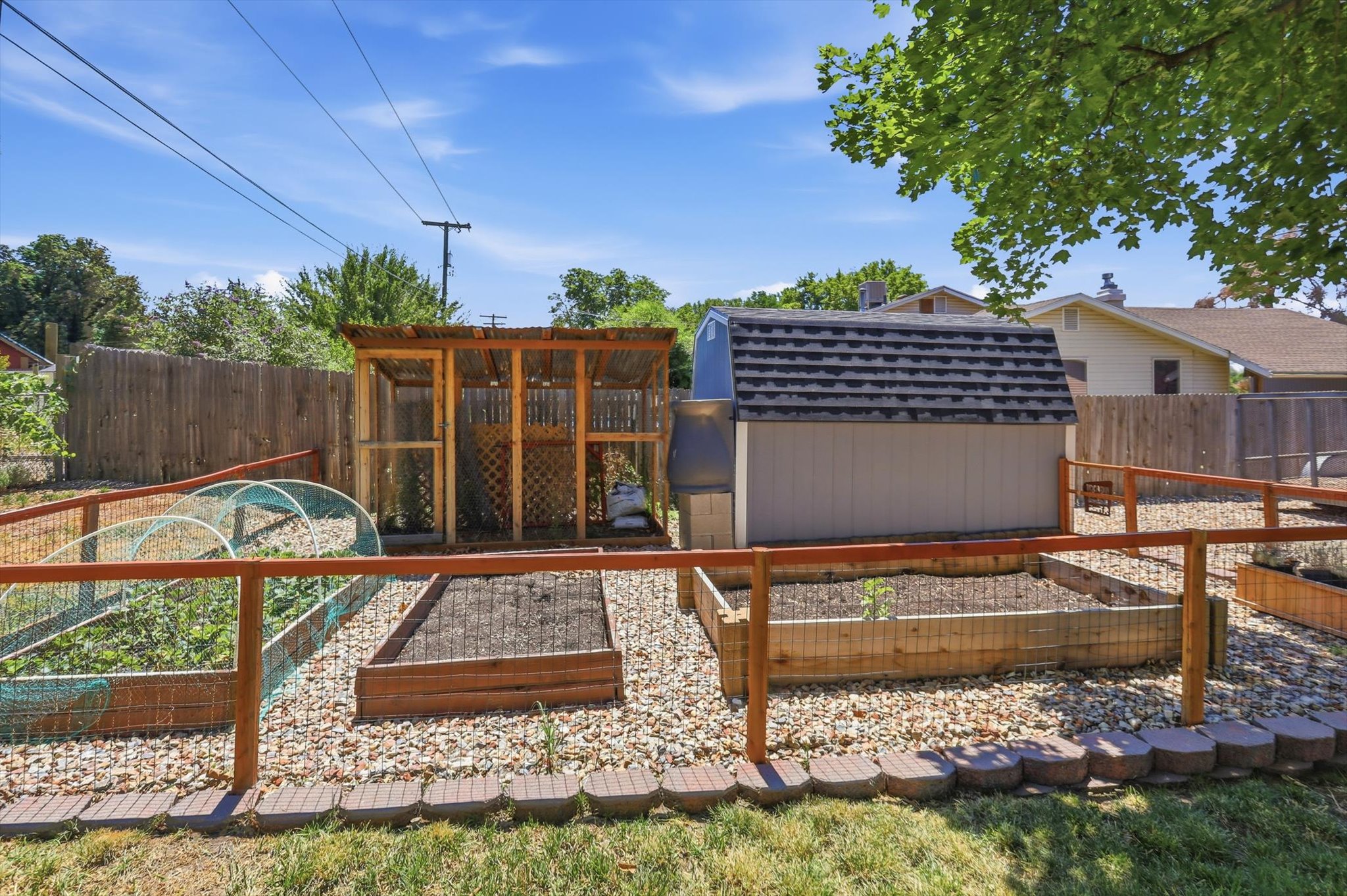Expansive backyard featuring multiple raised garden beds, a dedicated chicken coop structure, and a storage shed