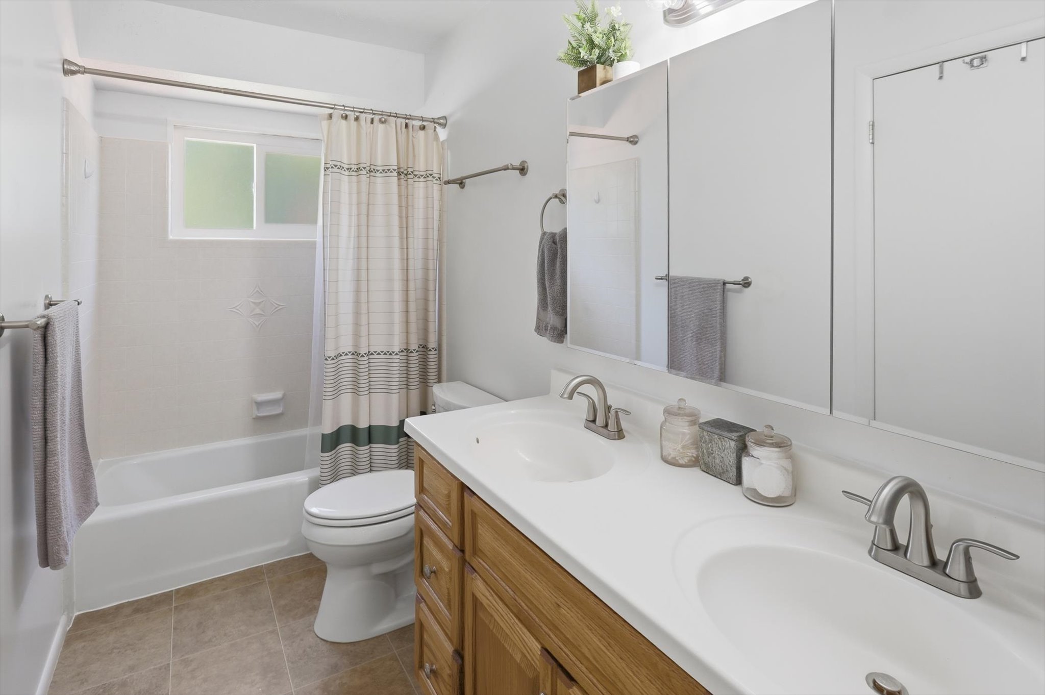 Dual vanity with integrated sinks, brushed nickel fixtures, wood-finish cabinetry, and overhead mirrored medicine cabinets