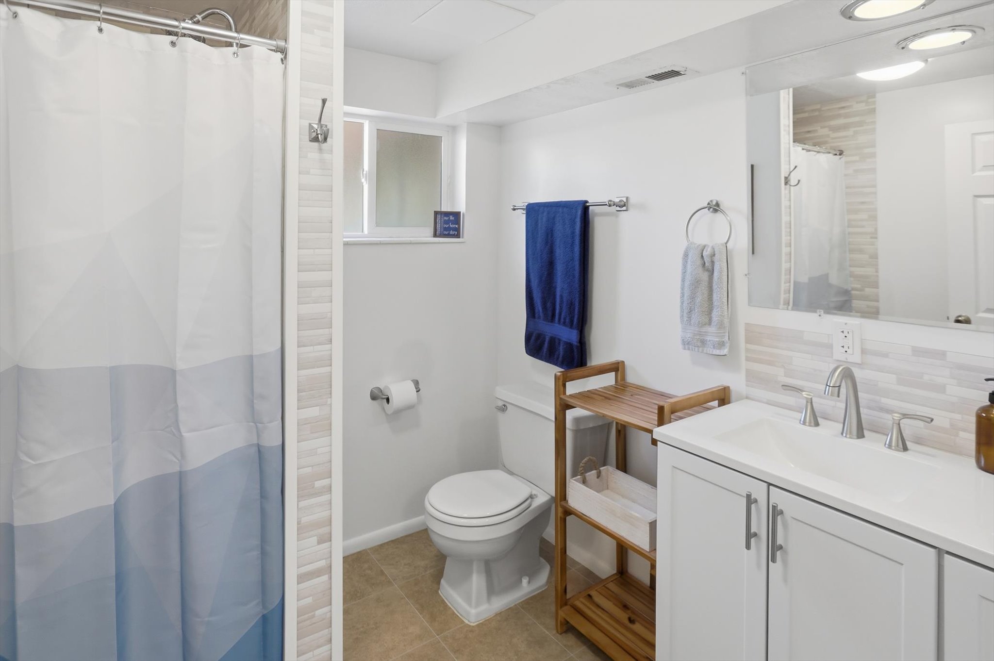 Bathroom featuring a white vanity with a single basin sink, brushed nickel faucet, and white cabinetry