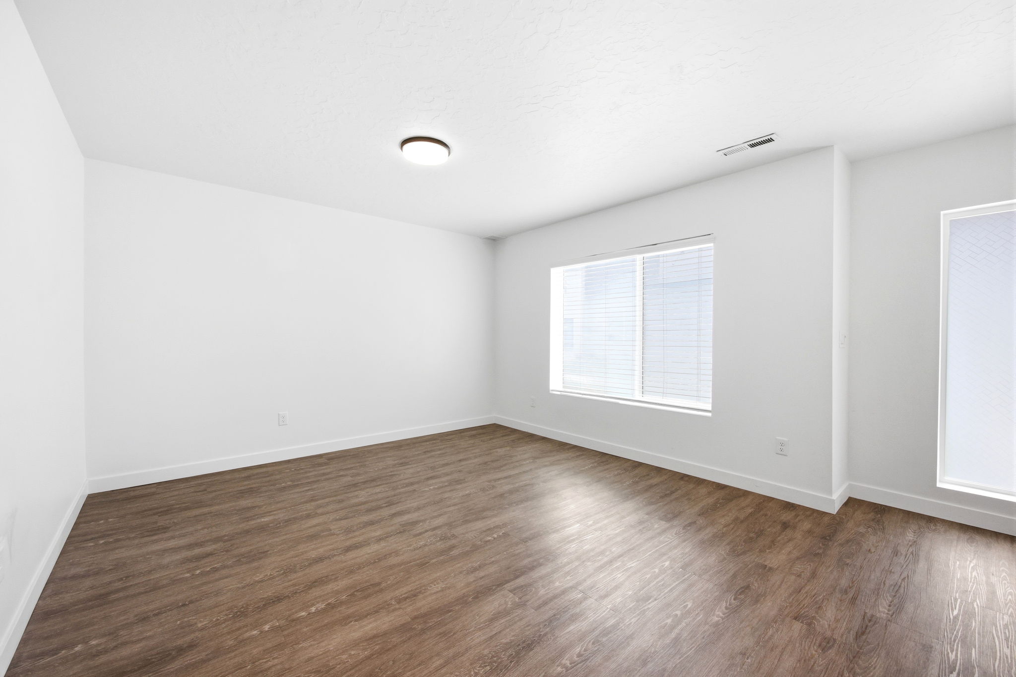 Spacious room featuring wood-finish flooring, white walls, and white trim