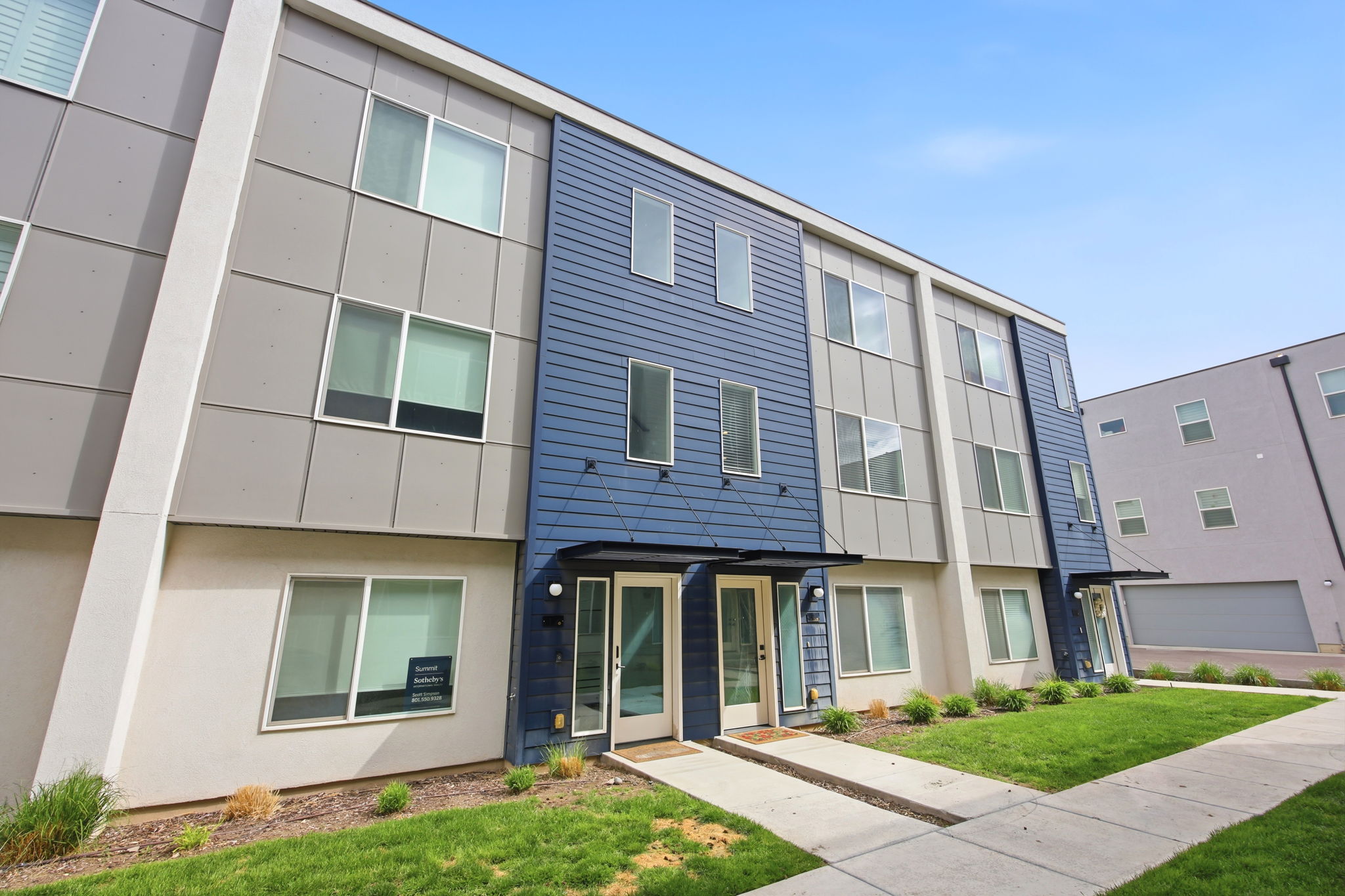 Modern multi-level exterior featuring blue horizontal siding and light gray paneling