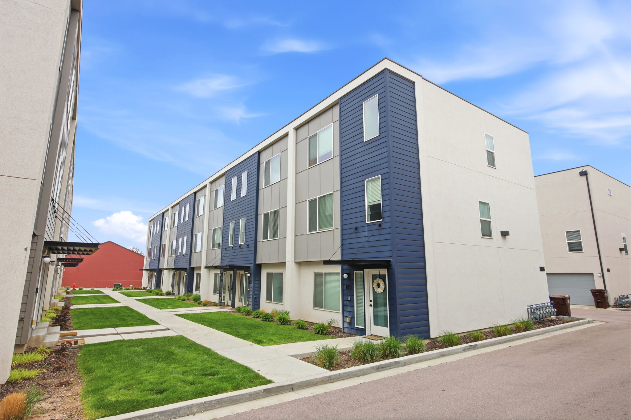 Modern multi-story facade featuring blue and gray siding with white stucco elements