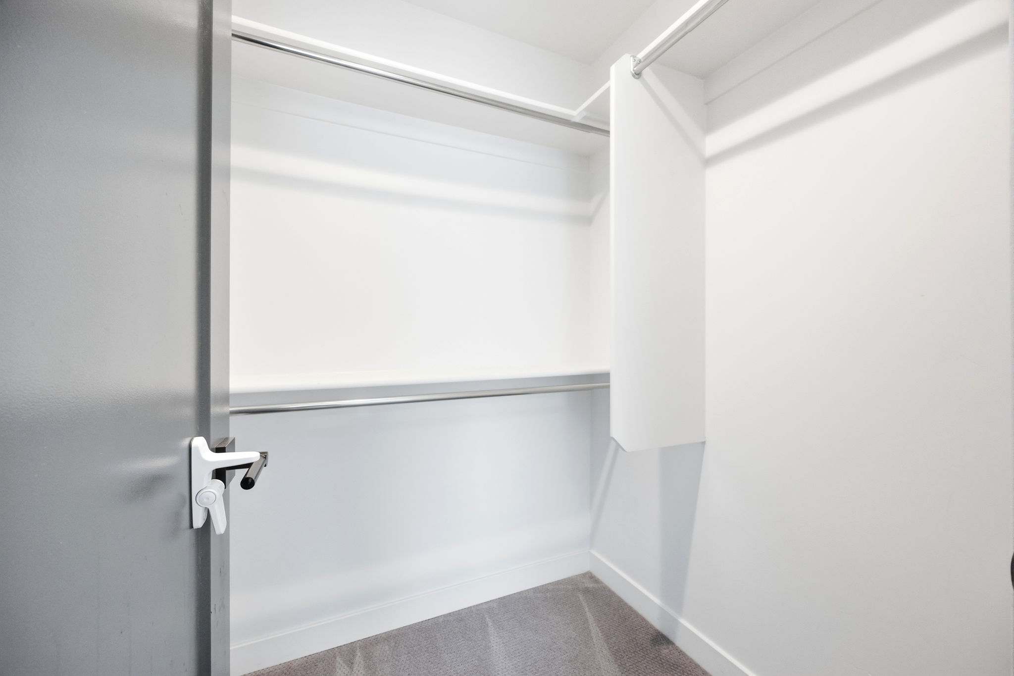 Walk-in closet featuring white walls, gray carpet, and two chrome hanging rods