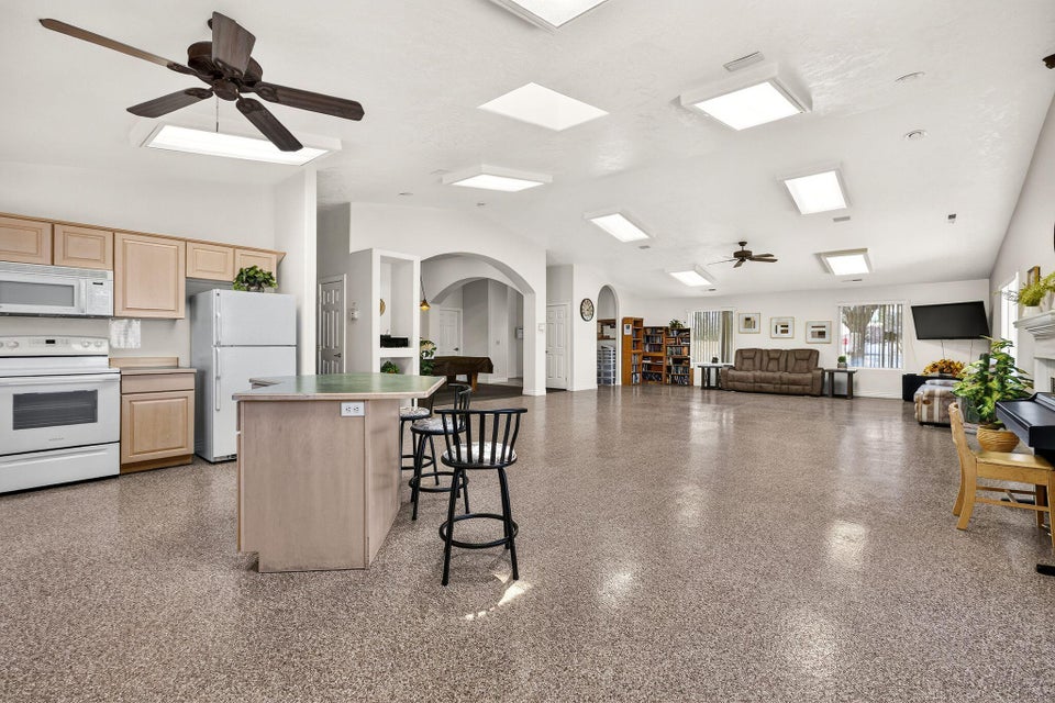 Expansive open-concept room featuring a functional kitchen island, multiple skylights, recessed lighting, ceiling fans, and durable epoxy flooring