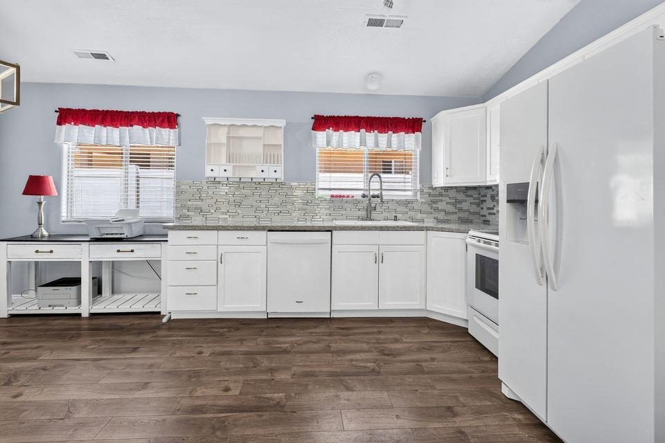 Kitchen featuring white cabinetry, stone-finish countertops, tile backsplash, and wood-finish flooring