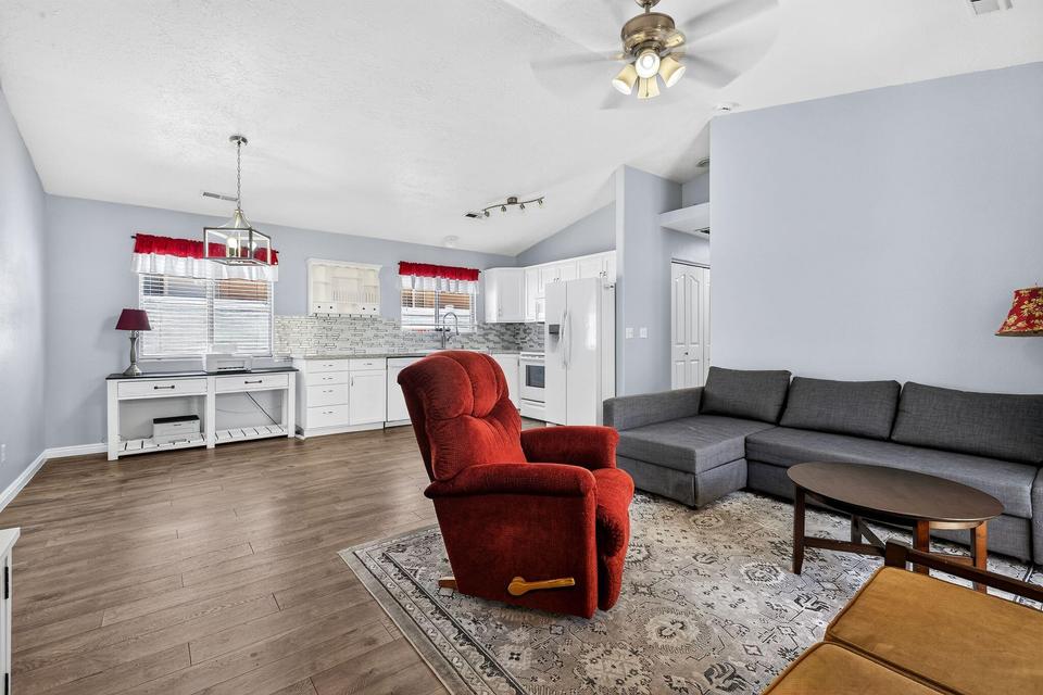 Open-concept living space featuring wood-finish flooring, vaulted ceilings, and a ceiling fan