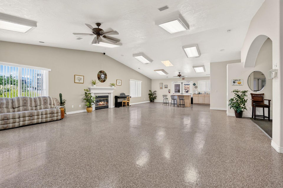Spacious open-concept room featuring high vaulted ceilings, durable composite flooring, and multiple ceiling fans