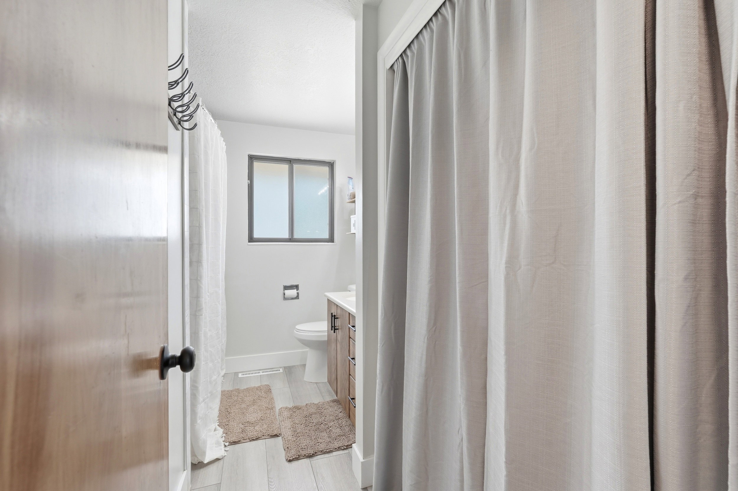 Bathroom featuring wood-finish flooring, a contemporary vanity with a laminate countertop, and a window with dark framing