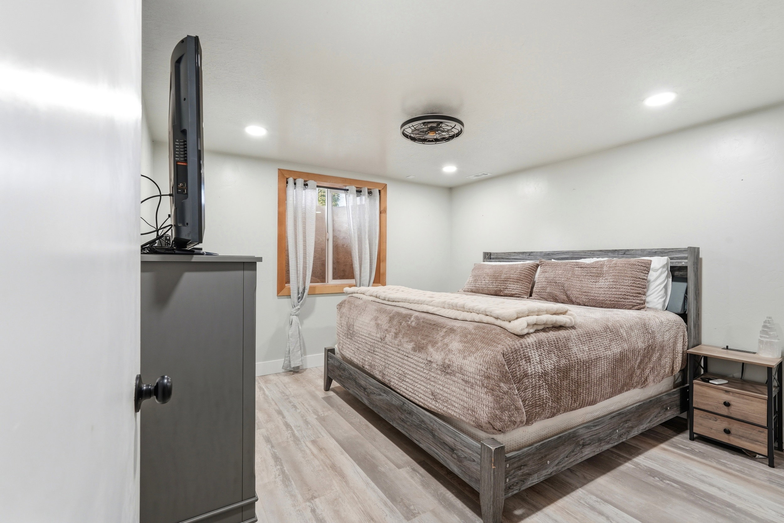Bedroom featuring light wood-finish flooring, recessed lighting, and a window with natural wood trim