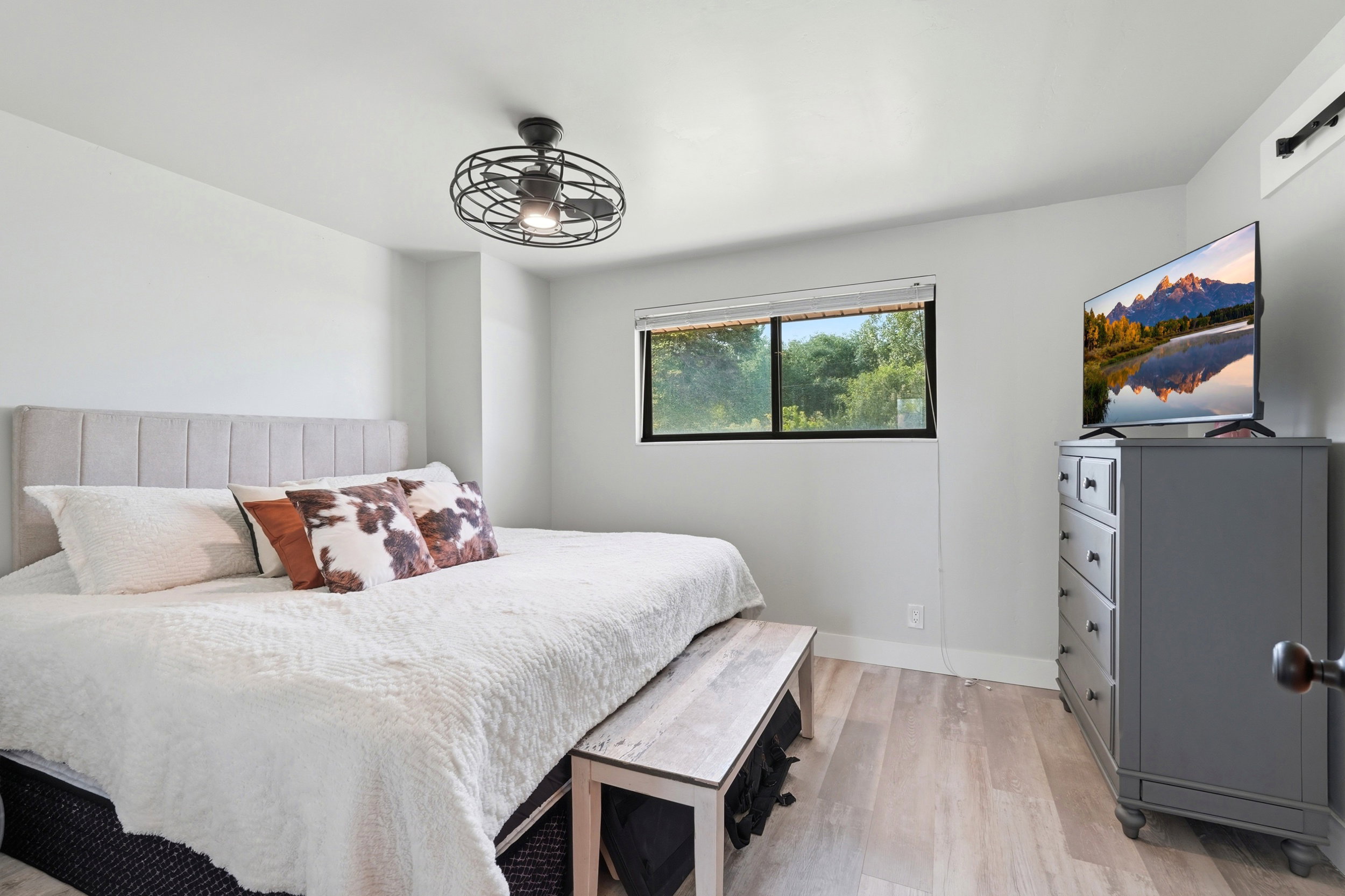 Bright interior featuring wood-finish flooring, a contemporary ceiling fan, and a wide window