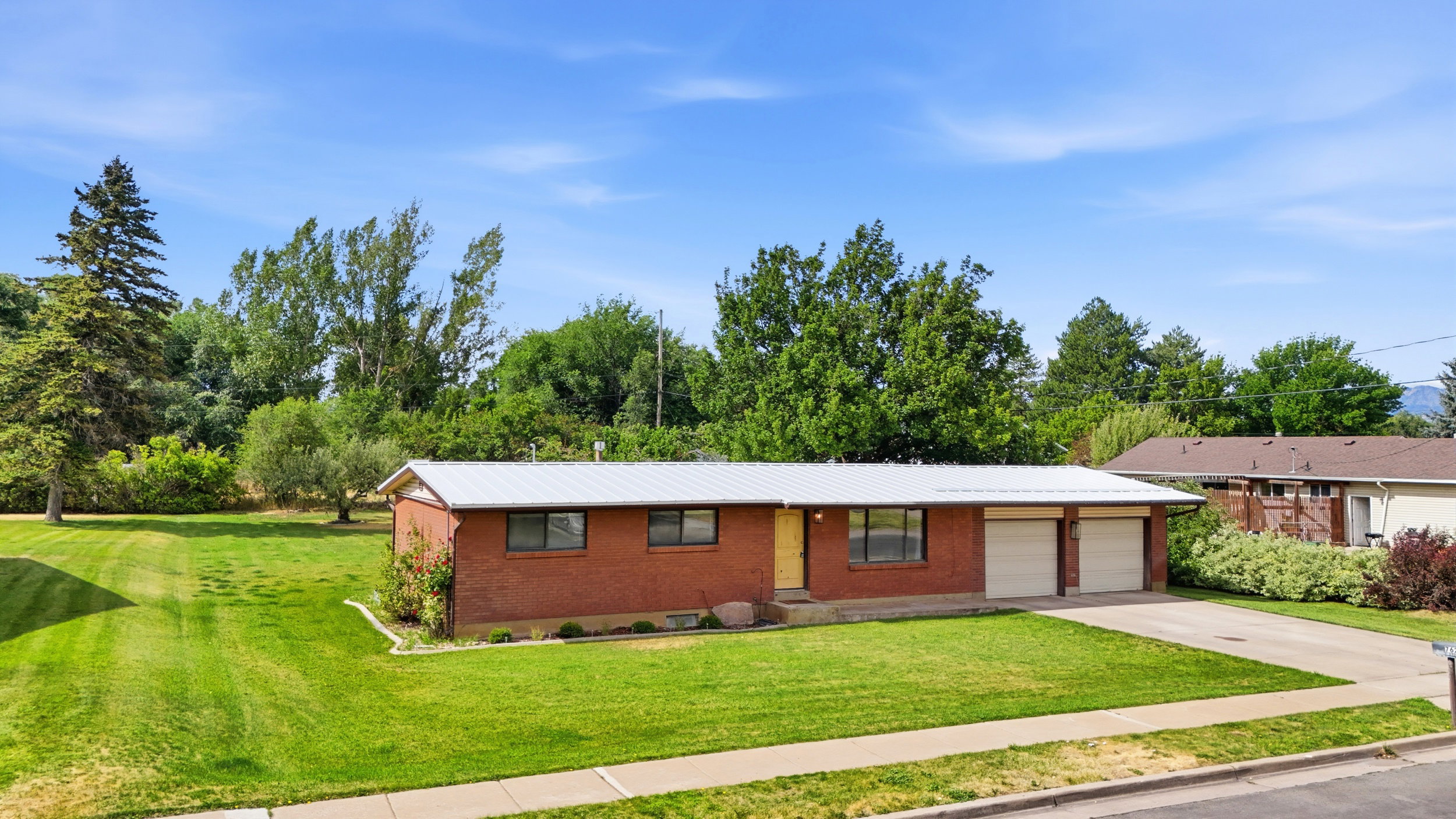 Brick ranch-style home featuring a metal roof and an attached two-car garage