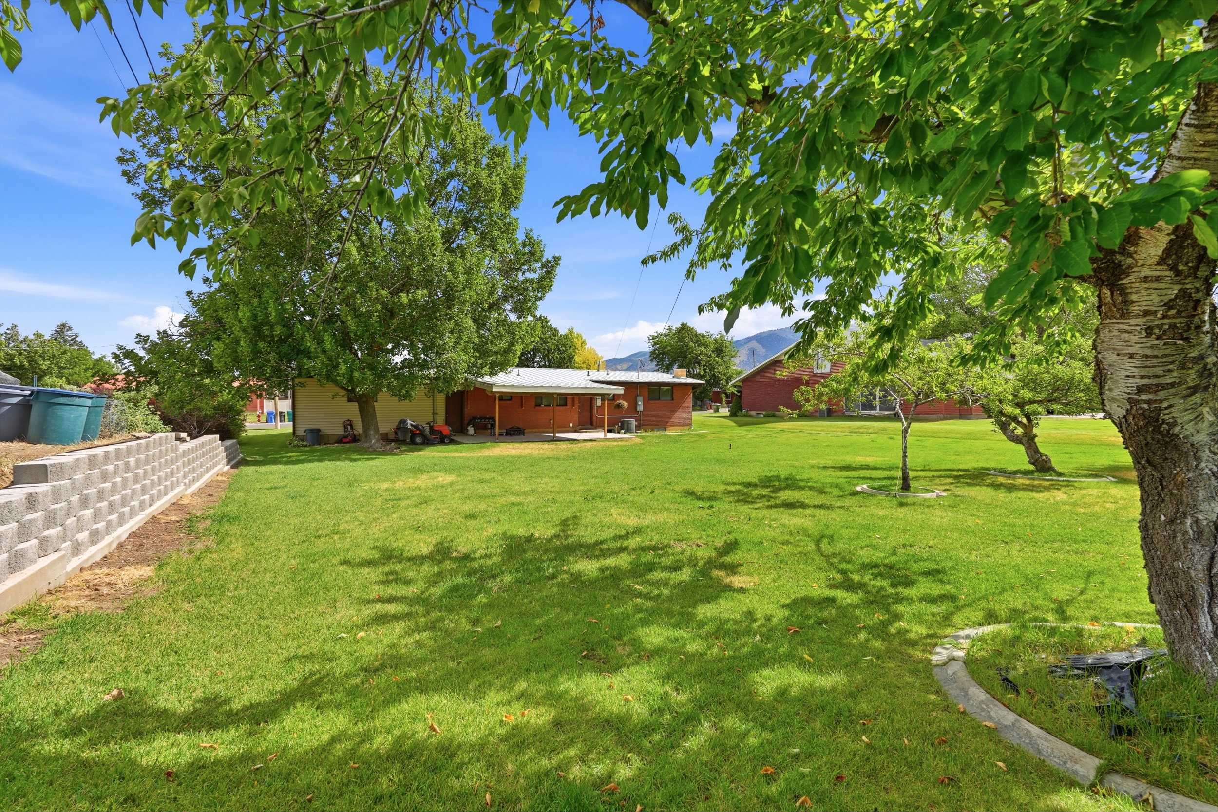 Expansive green lawn with mature trees providing natural shading