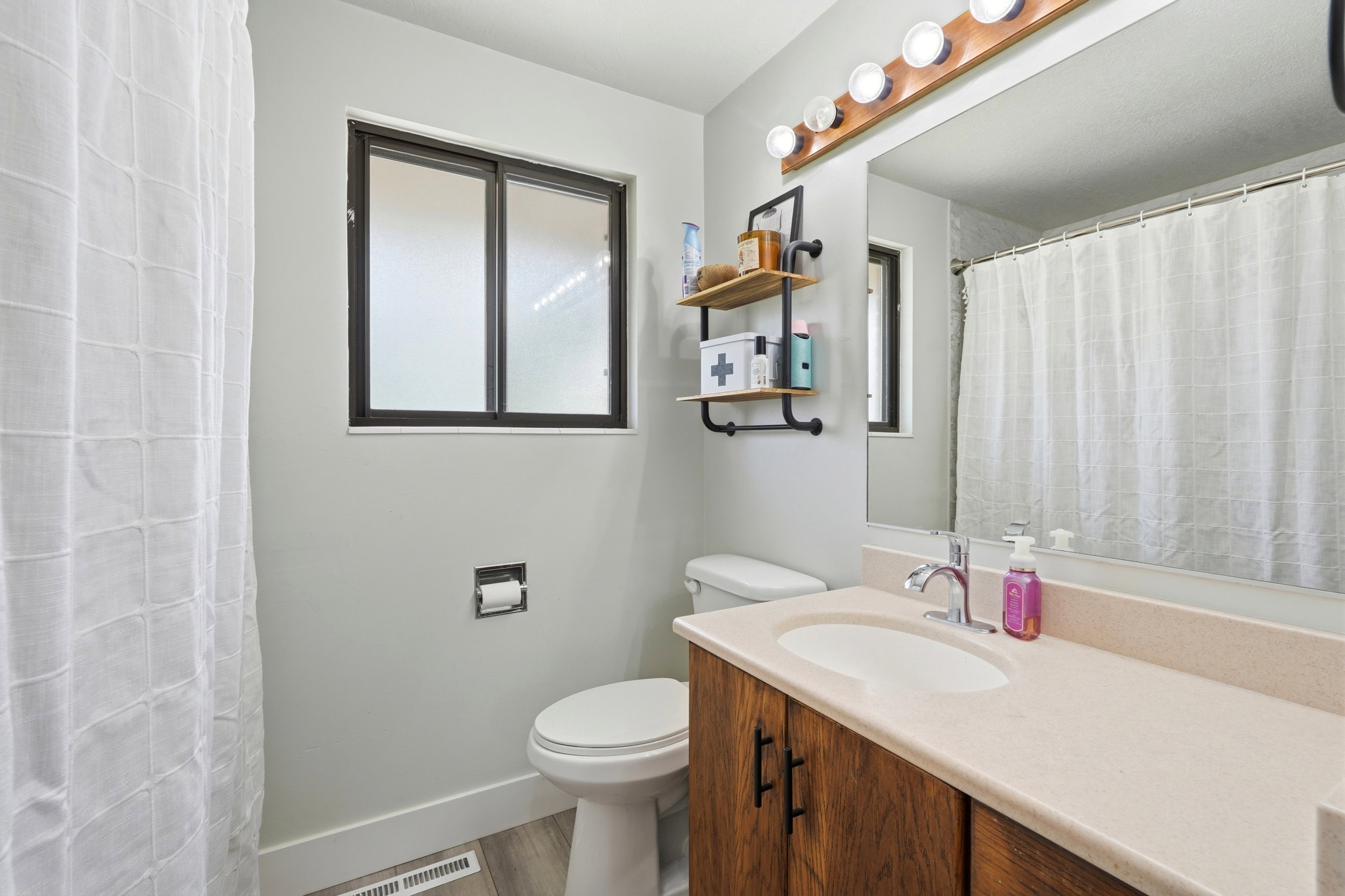 Bathroom featuring a wood-finish vanity with an integrated sink and light-toned countertop