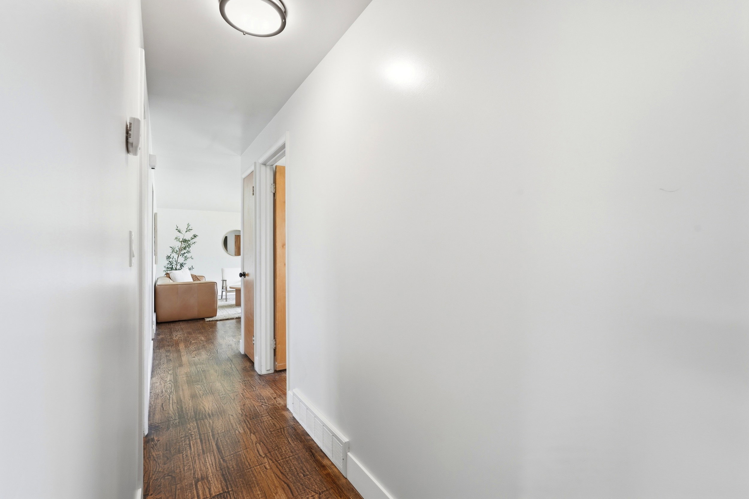 Hallway featuring wood-finish flooring, white baseboards, and a flush-mount ceiling light
