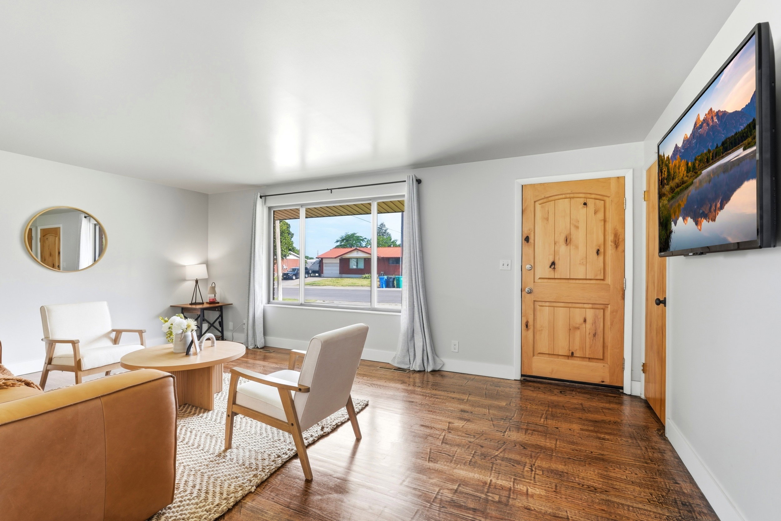 Living area featuring rich wood-finish flooring, light gray walls, and a prominent front entry door with vertical paneling