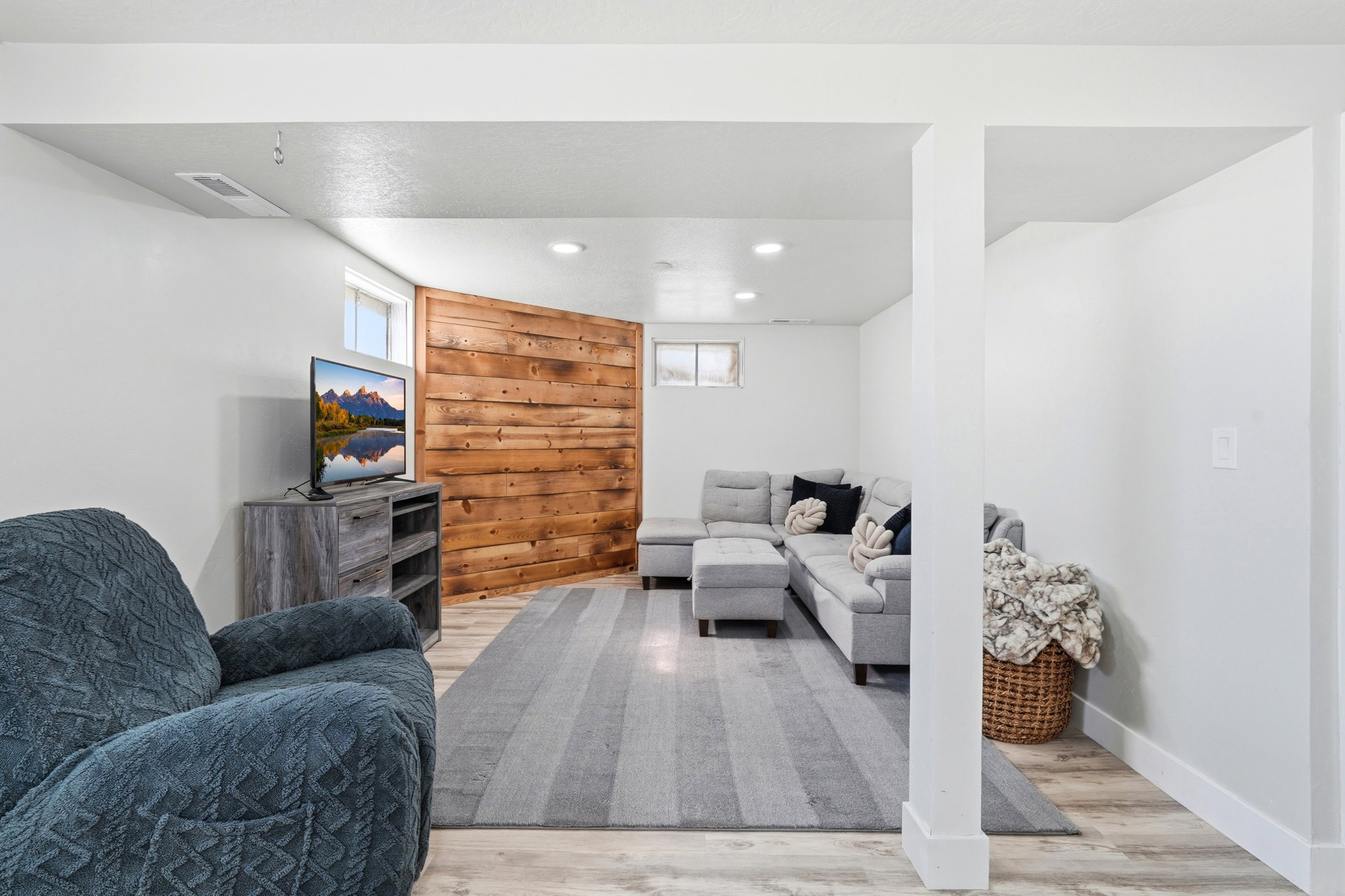 Spacious living area featuring light wood-finish flooring, recessed lighting, and a prominent wood accent wall