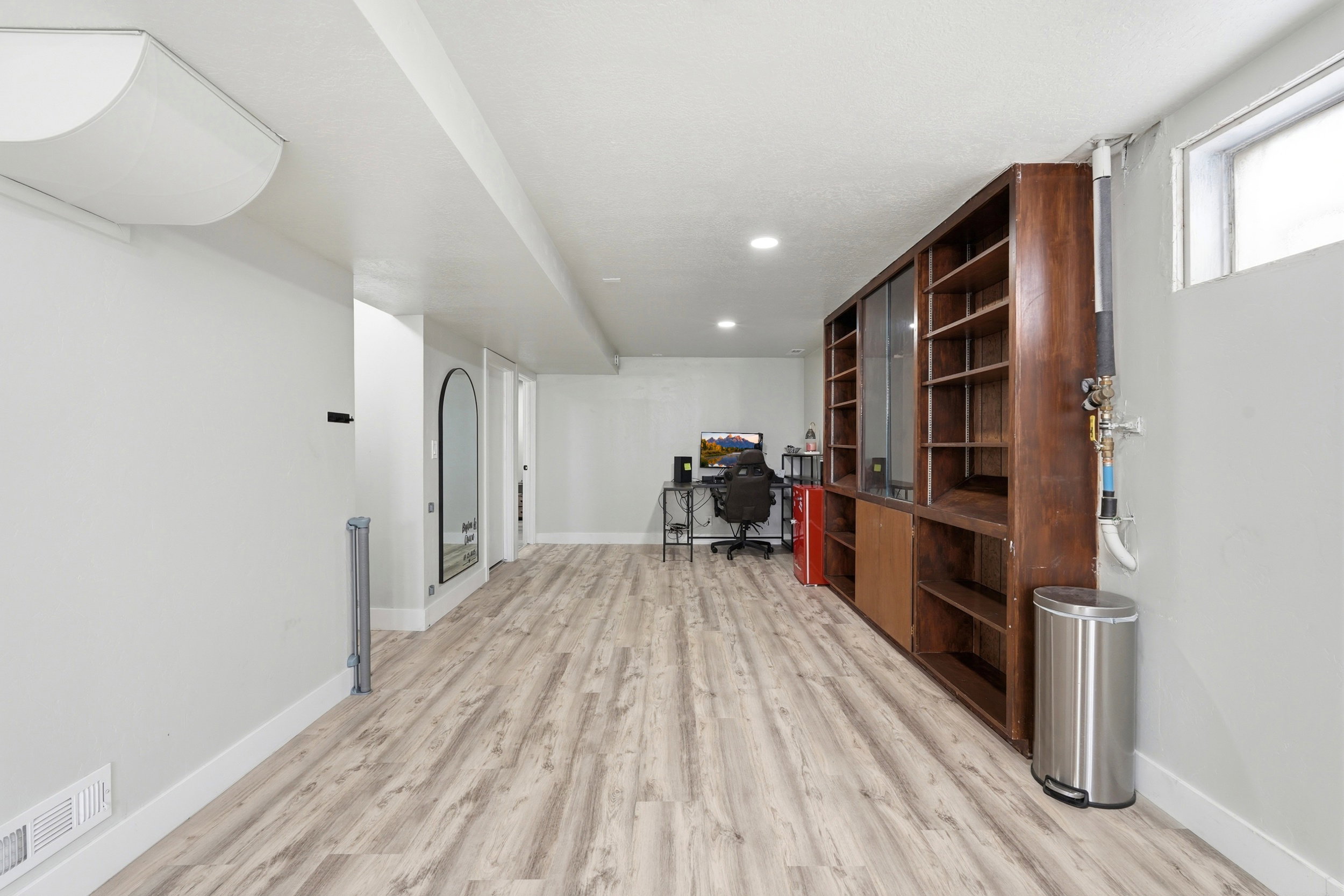 Spacious interior featuring wood-finish flooring, recessed lighting, and a built-in wall unit with shelving and sliding doors
