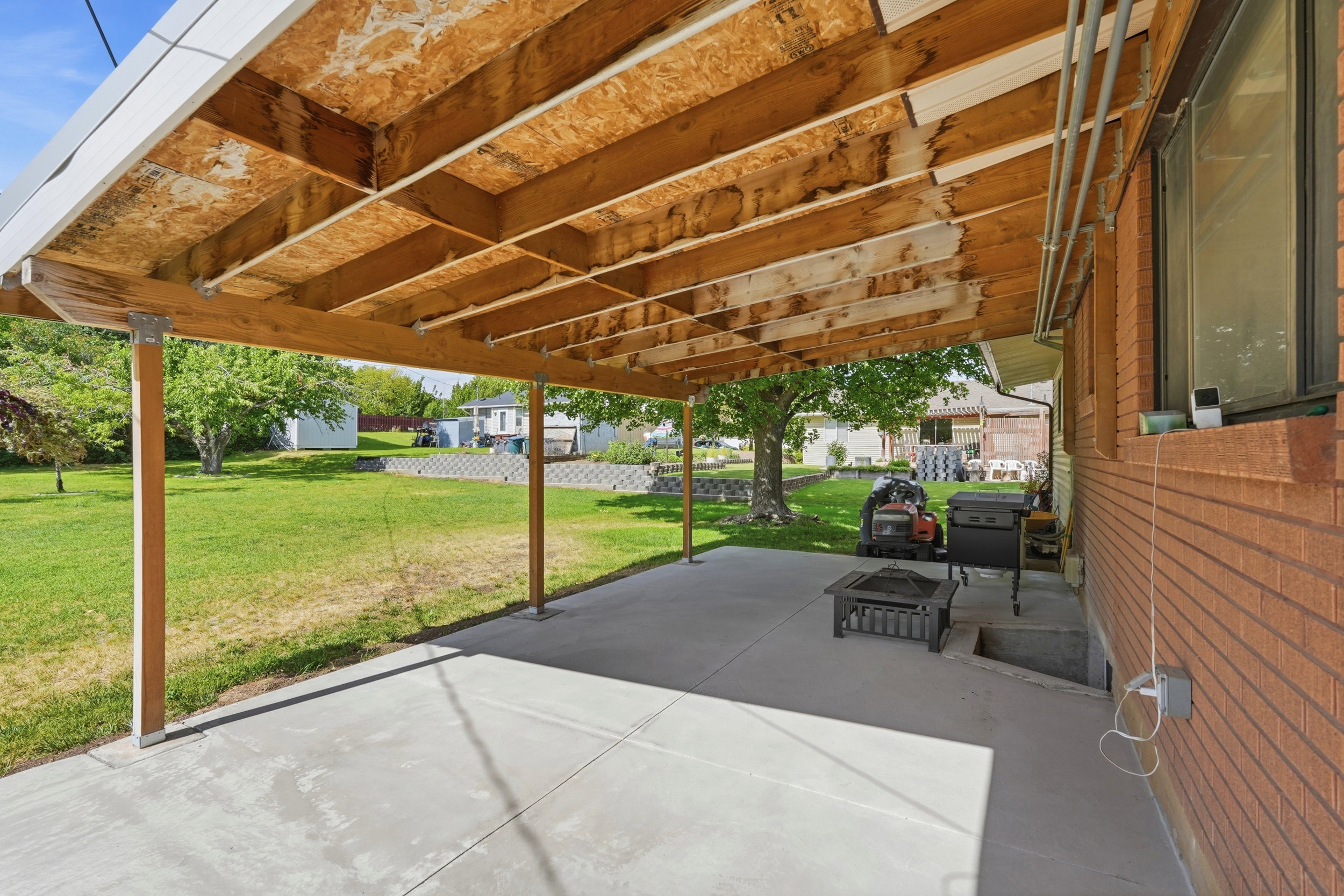 Covered concrete patio extending to a spacious lawn