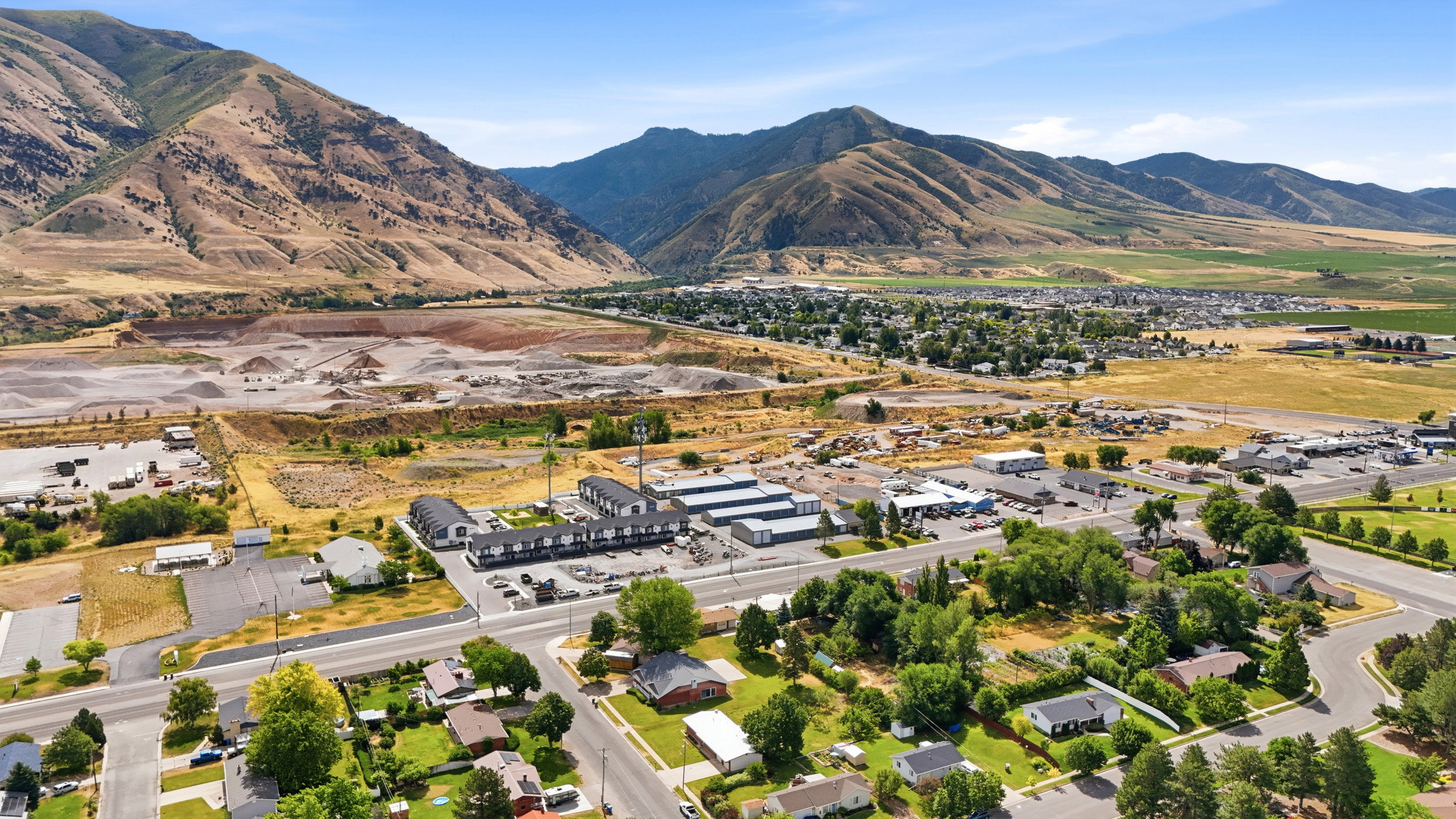 Expansive aerial perspective showcasing a residential neighborhood with surrounding commercial structures and agricultural fields