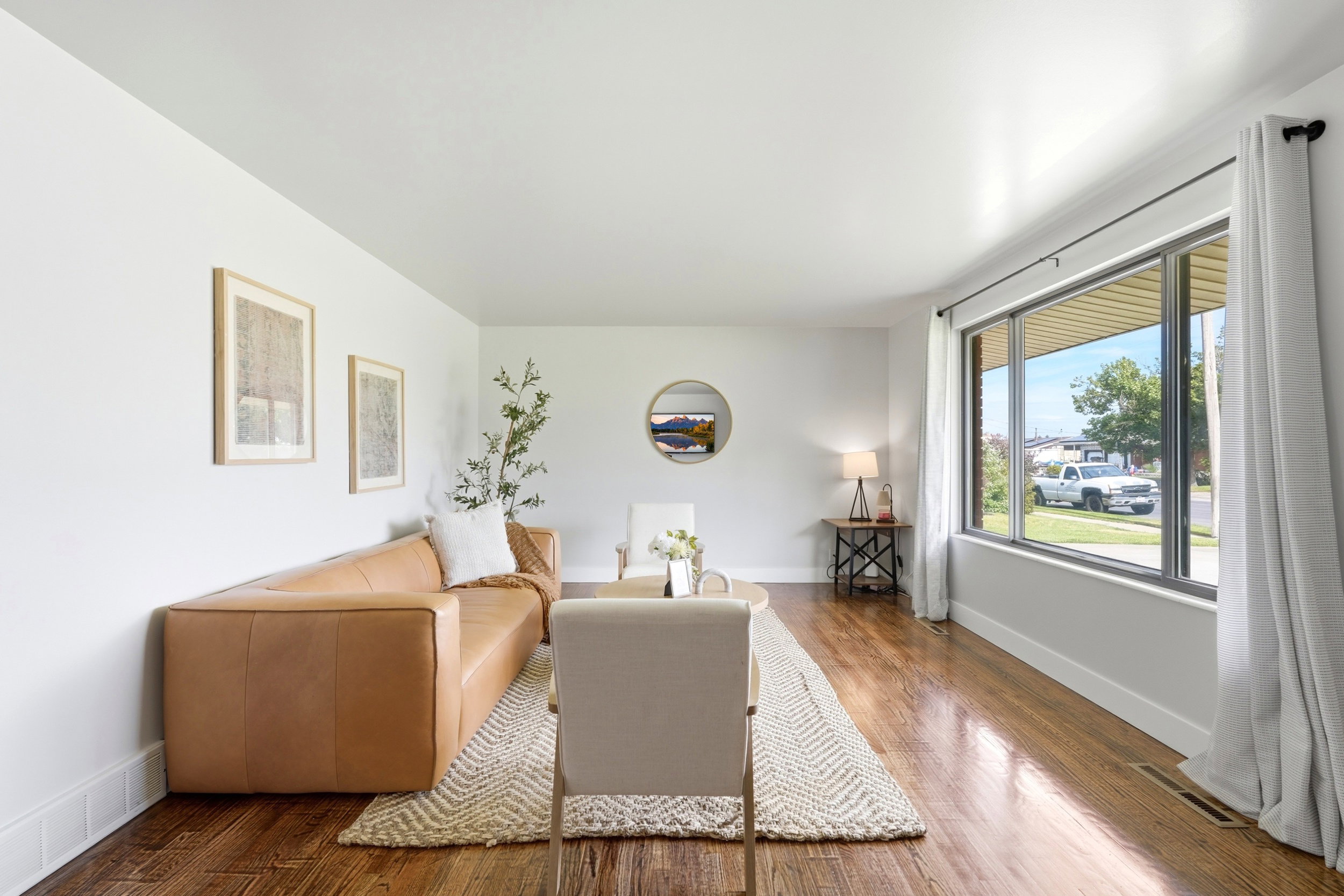 Spacious living area featuring expansive windows, wood-finish flooring, and white baseboards
