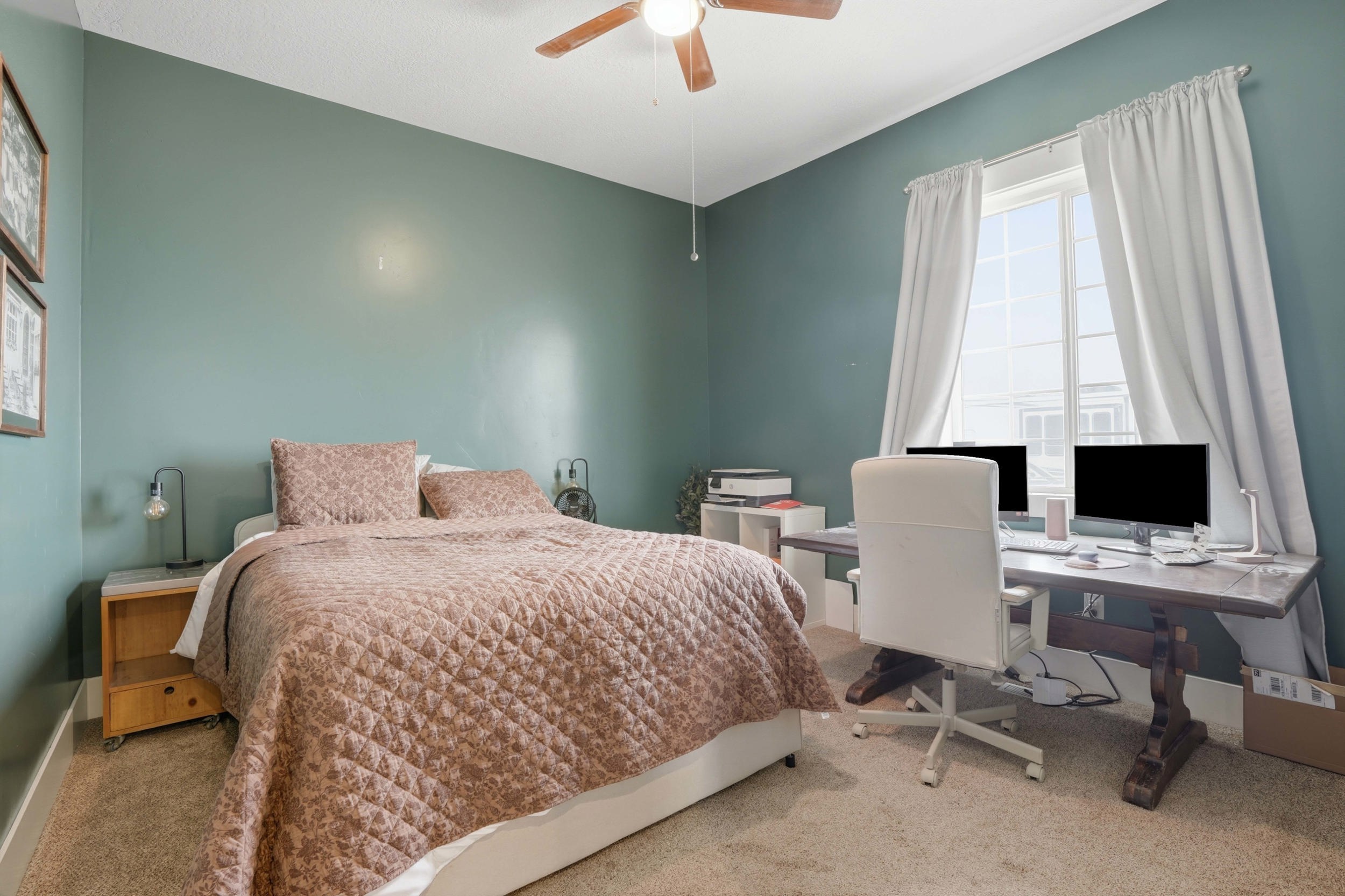 Spacious room featuring carpet flooring, a ceiling fan, and a large window with white curtains