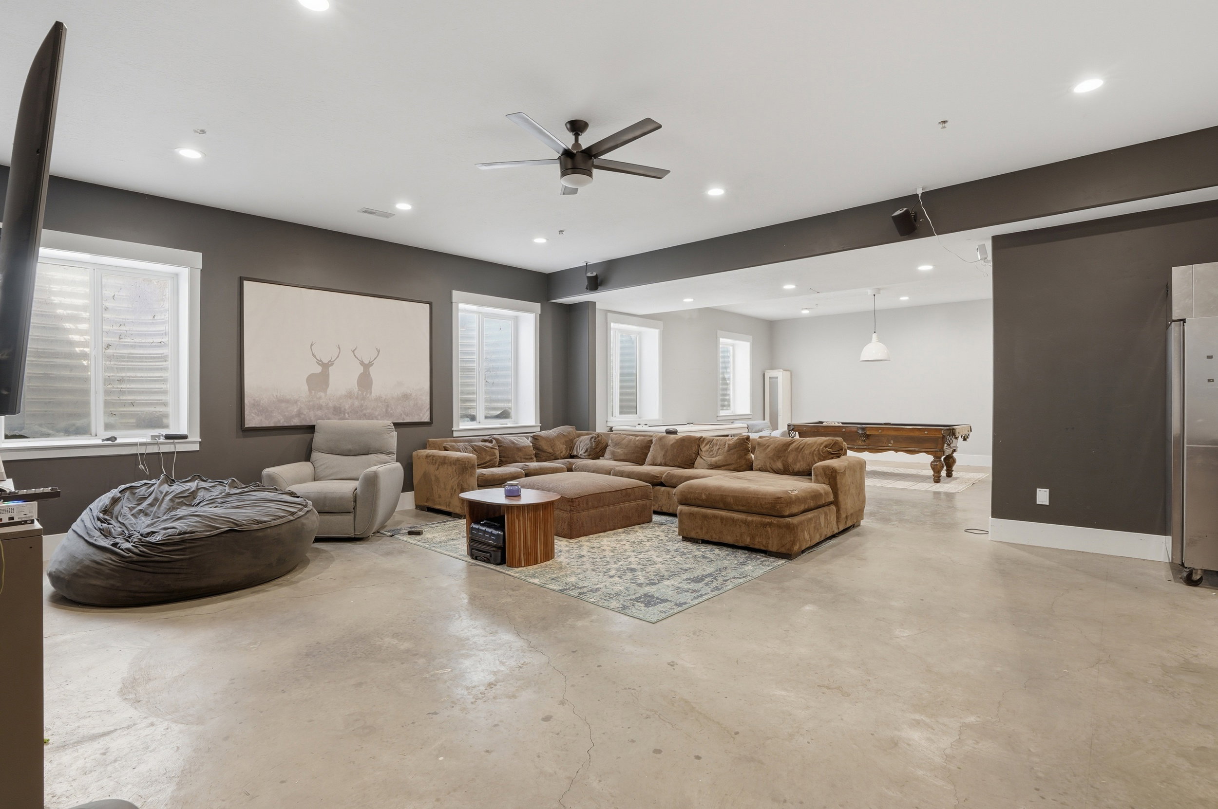 Spacious open-concept lower level with concrete flooring, recessed lighting, and a ceiling fan